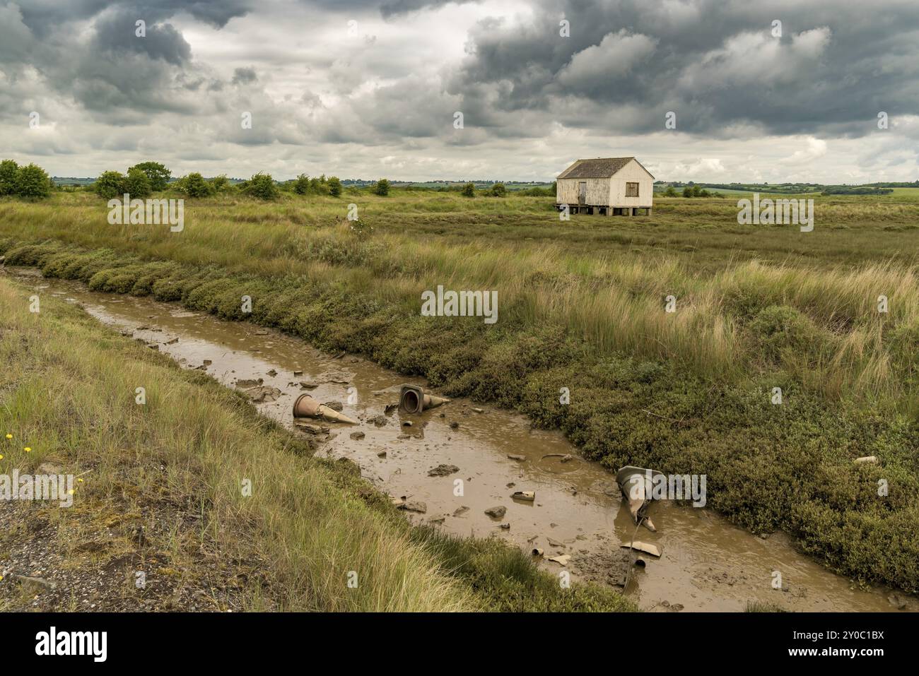 Haus auf Stelzen und Pylonen im Schlamm des Sumpfgebiets in der Nähe des River Crouch, Wallasea Island, Essex, England, Großbritannien Stockfoto