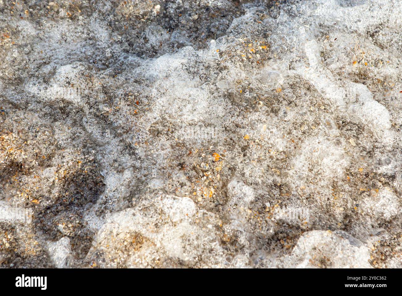 Muschelsplitter und Sand unter Meerwasser und Schaumblasen mit Bewegungsunschärfe Stockfoto