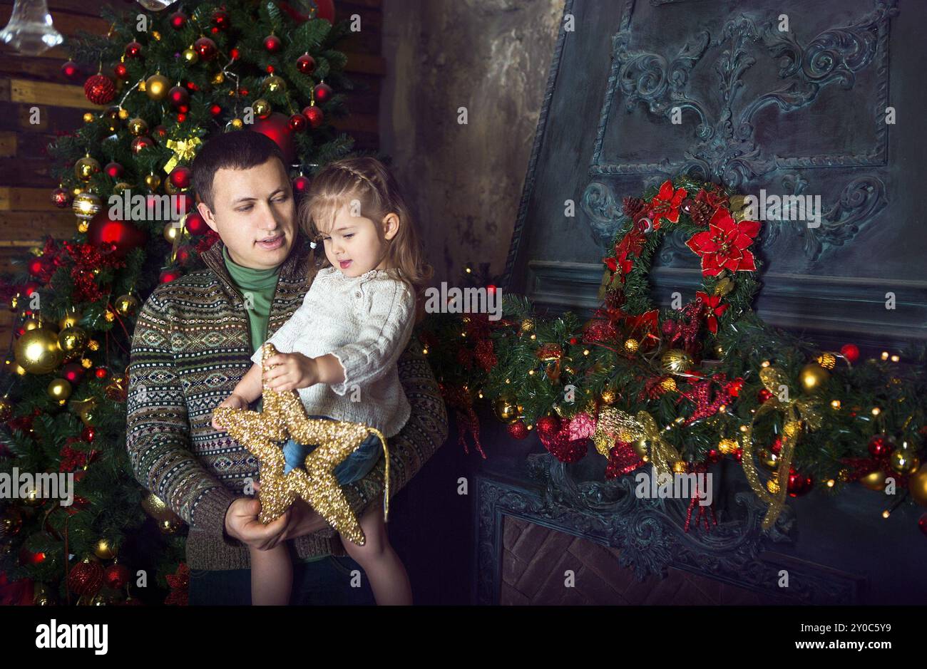 Glücklicher Vater und seiner kleinen Tochter schmücken den Weihnachtsbaum zu Hause Stockfoto