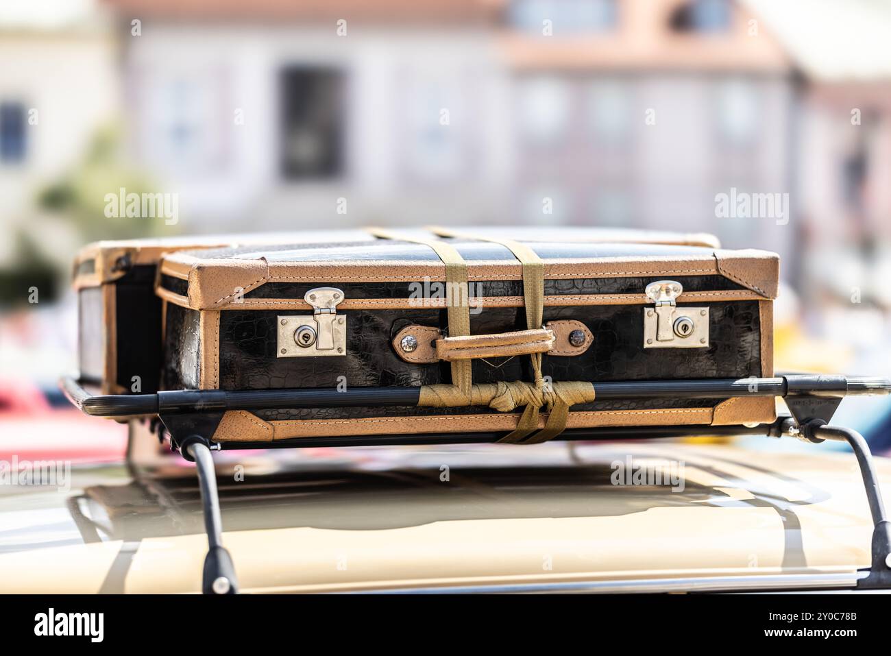 Alte Koffer auf der Motorhaube eines historischen Autos irgendwo in der Stadt. Unterhaltsames Reisekonzept. Stockfoto