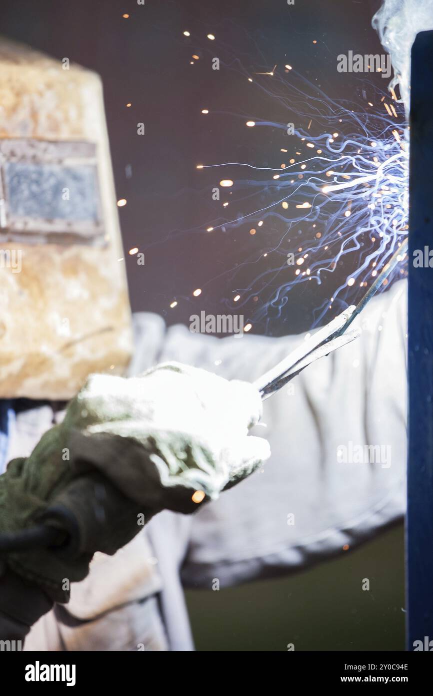 Schwere Industrie Schweißgerät Arbeiter in Schutzmaske Hand arc Schweißbrenner arbeiten auf Metall Bau Stockfoto