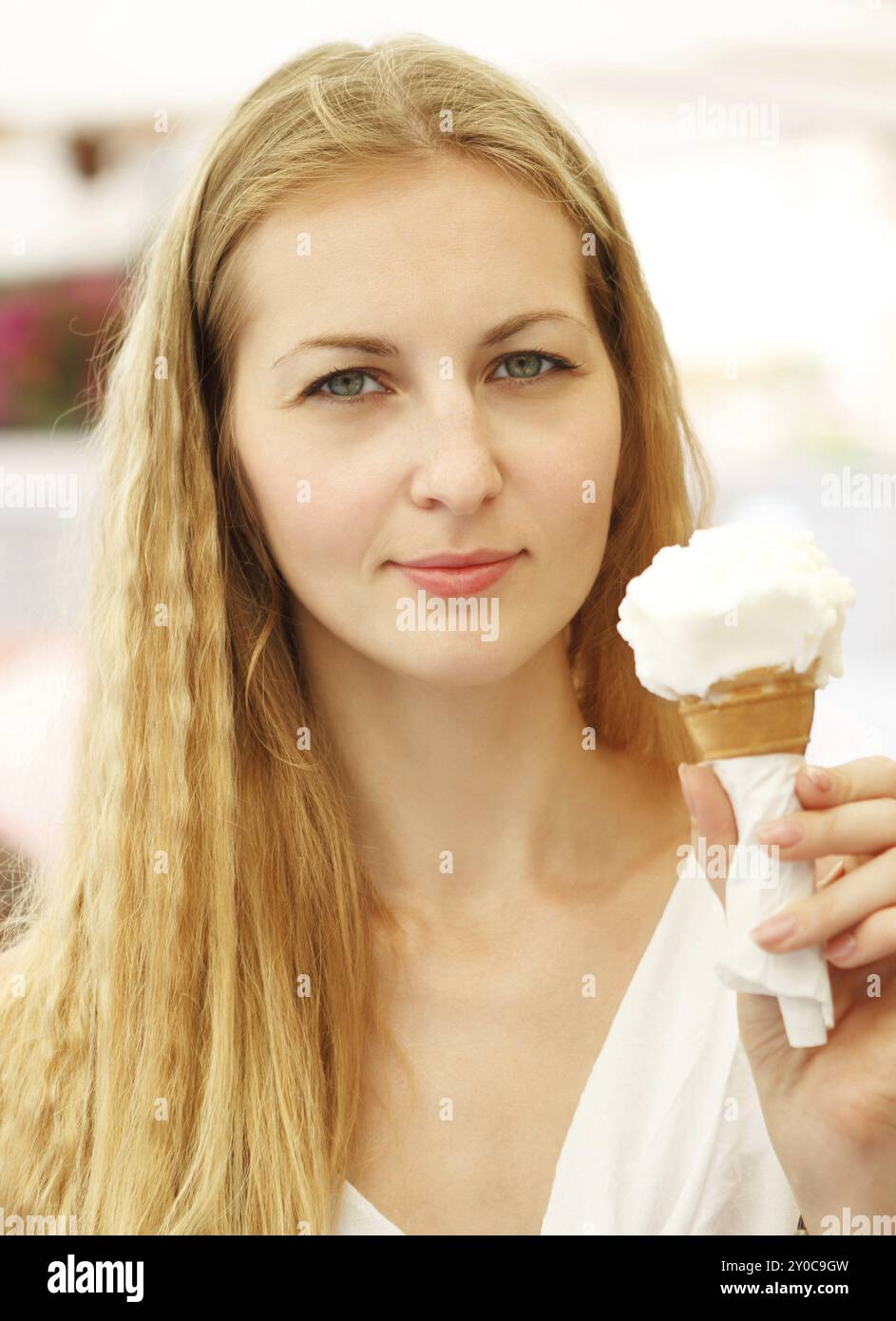 Junge blonde Frau, die draußen Eisbecher in der Hand hält Stockfoto