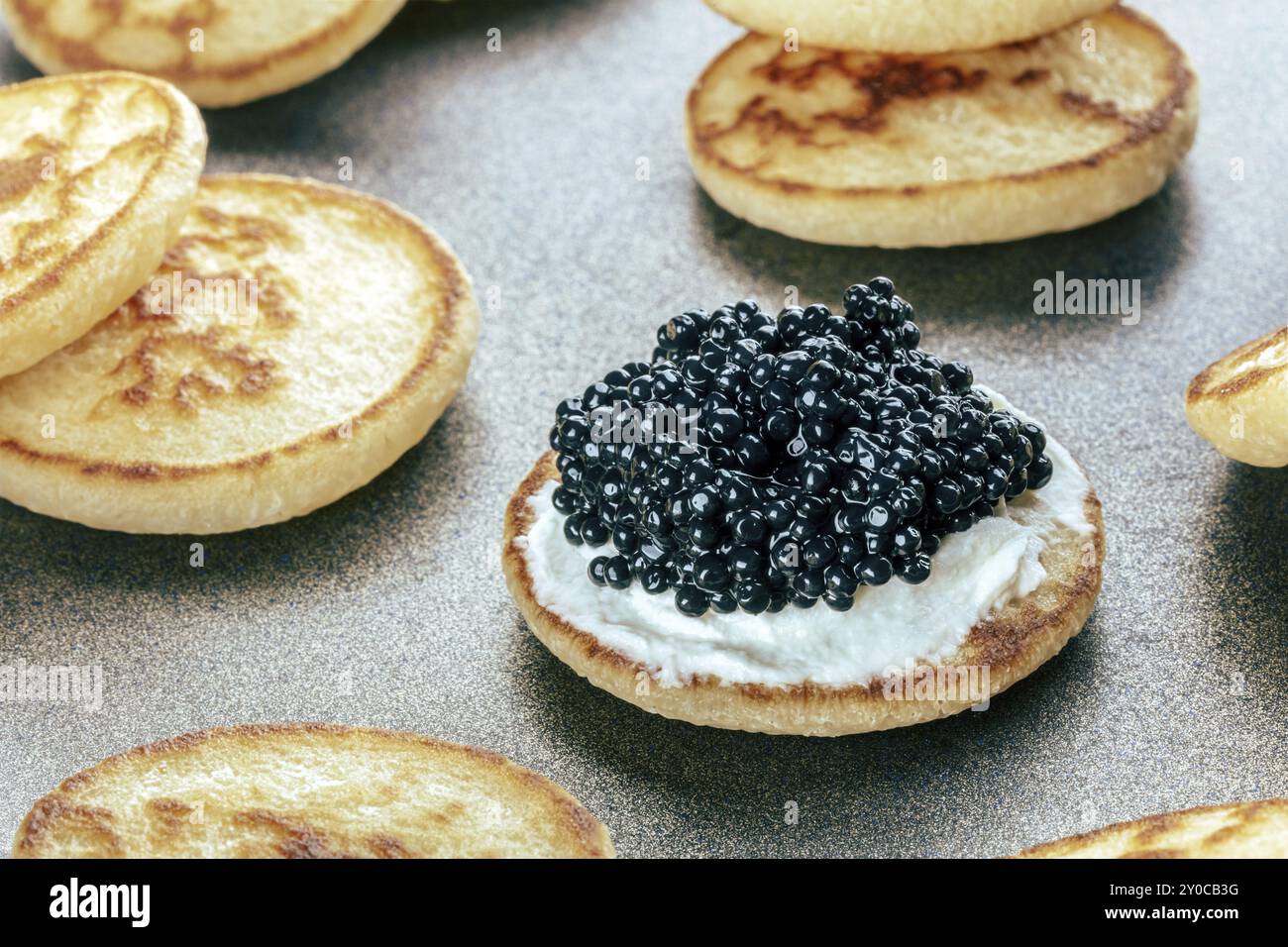 Blinis mit schwarzem Kaviar und Frischkäse, auf festlichem Gericht, Mini-Pfannkuchen, eine elegante Vorspeise, Lebensmittelfotografie Stockfoto