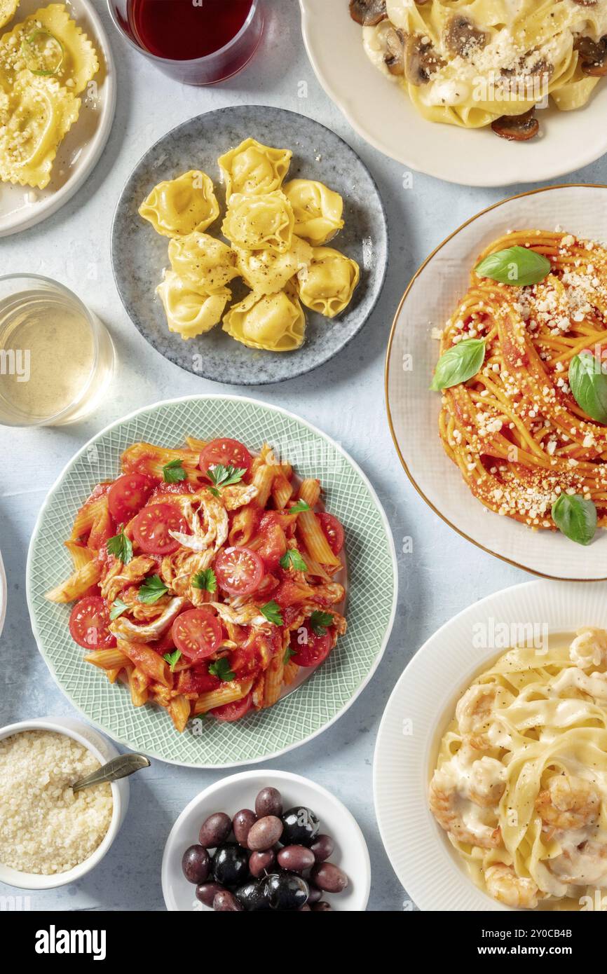 Italienische Pasta, verschiedene Gerichte, Overhead Flat Lay Shot. Spaghetti, Penne mit Huhn, Garnelen-Pappardelle, geriebenem Parmesankäse, Wein und Oliven Stockfoto