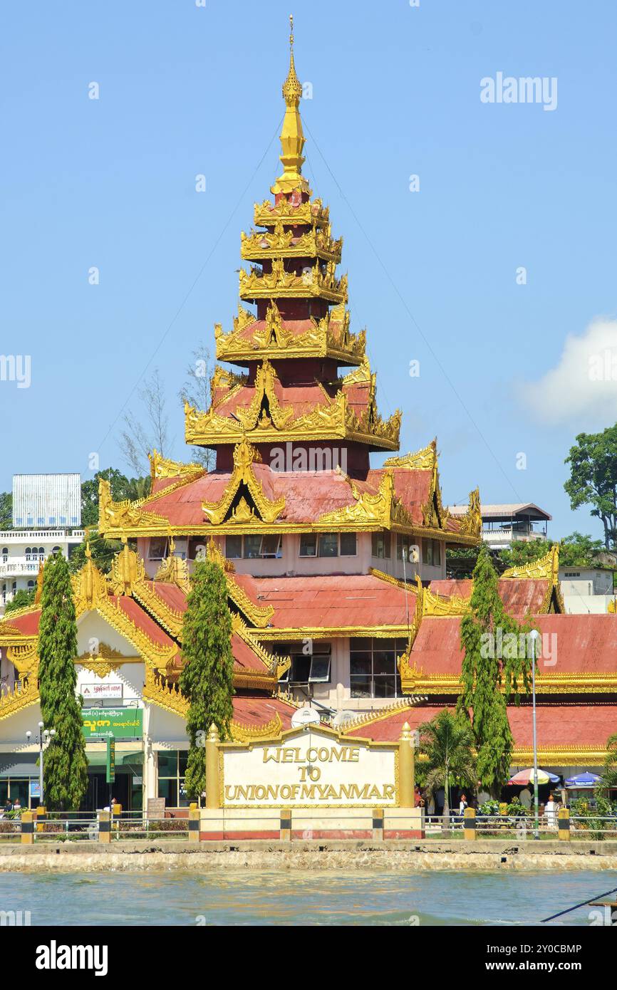 Goldene und weiße Mauer mit Begrüßung Willkommen in Union of Myanmar am Ufer der Grenzstadt Kawthaung, dahinter große Pagode mit goldenem Ro Stockfoto