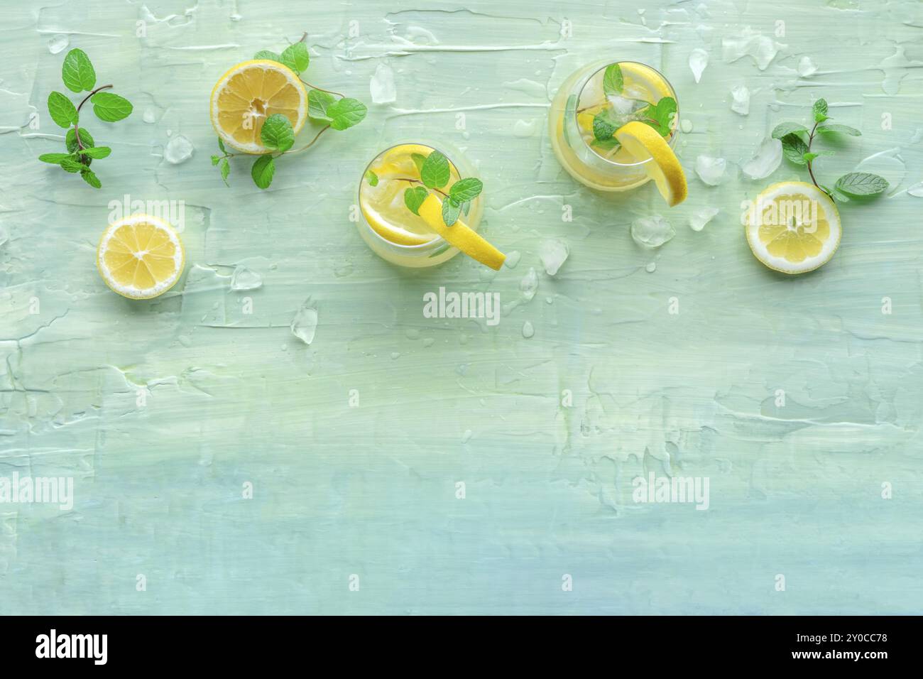 Limonade mit Minze. Zitronenwasser trinken mit Eis, zwei Gläser und Zitronen auf blauem Hintergrund, von oben aufgenommen mit einem Platz für Text. Entgiftungsgetränk. Stockfoto