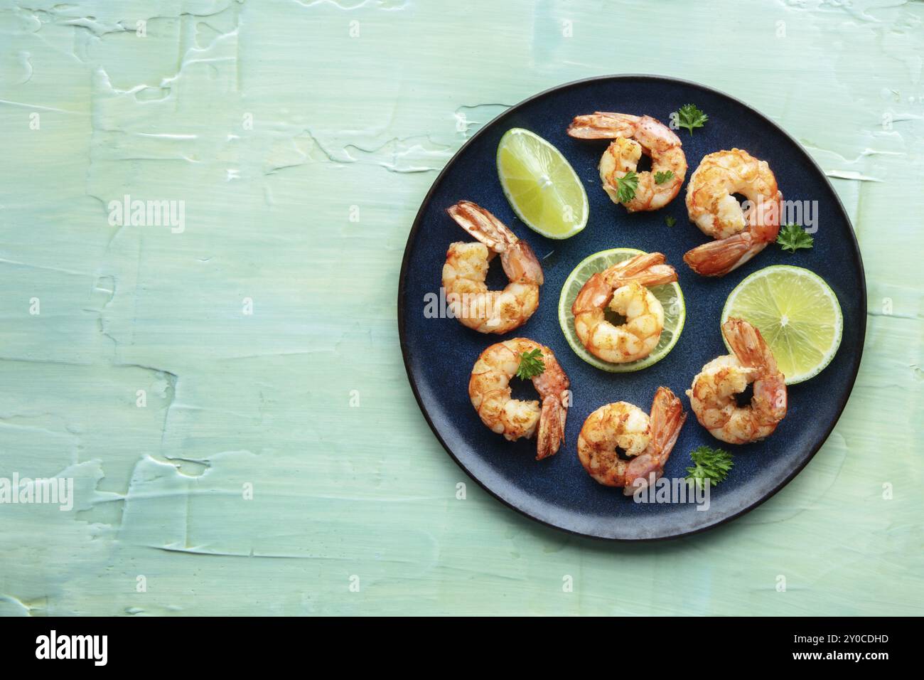 Shrimps, Overhead Flat Lay Shot auf blauem Hintergrund mit Kopierraum. Gegrillte Garnelen mit Limette und scharfem Meeresfrüchtegericht Stockfoto