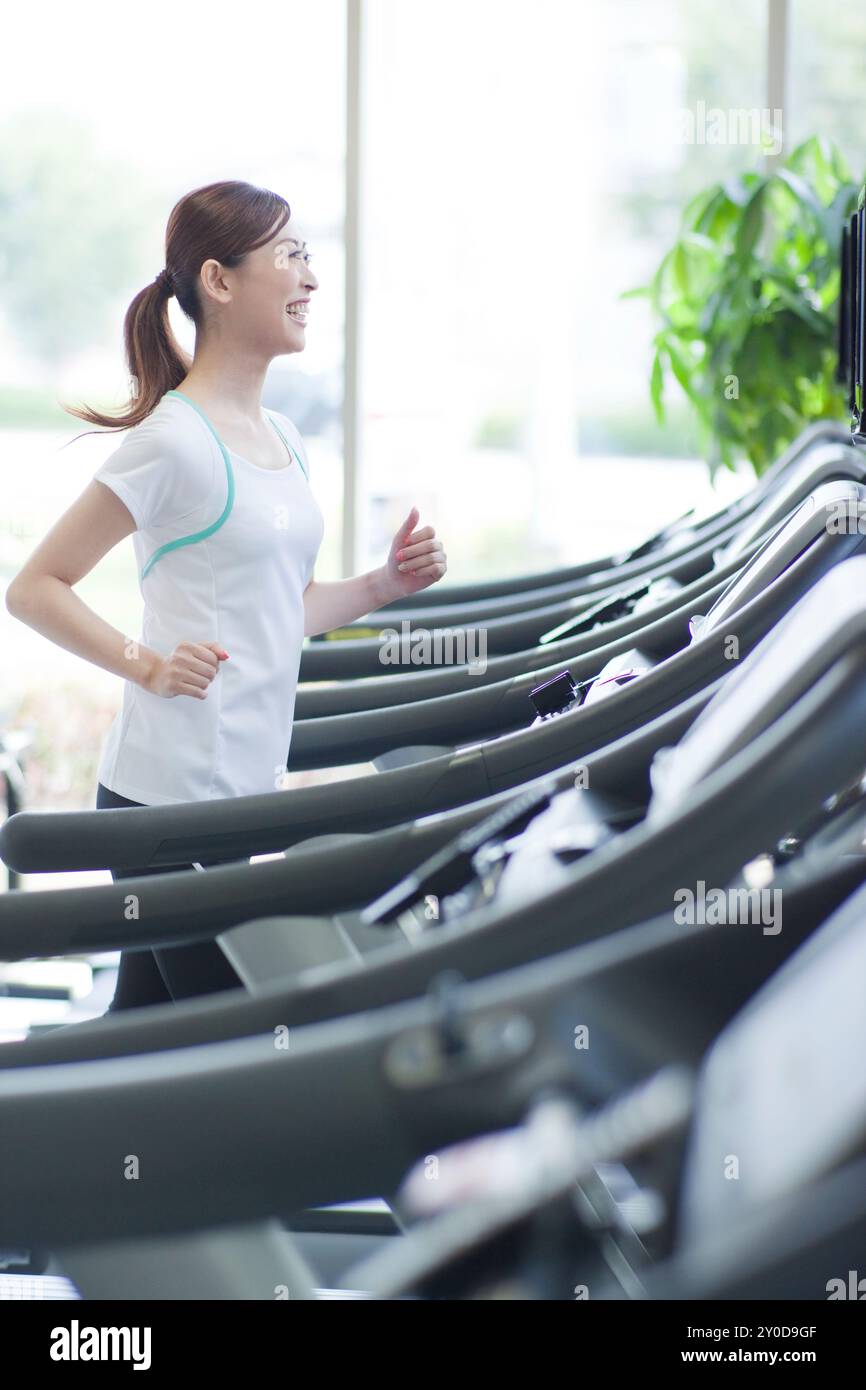 Eine Frau, die in einem Fitnessstudio mit einem Lächeln im Gesicht trainiert Stockfoto