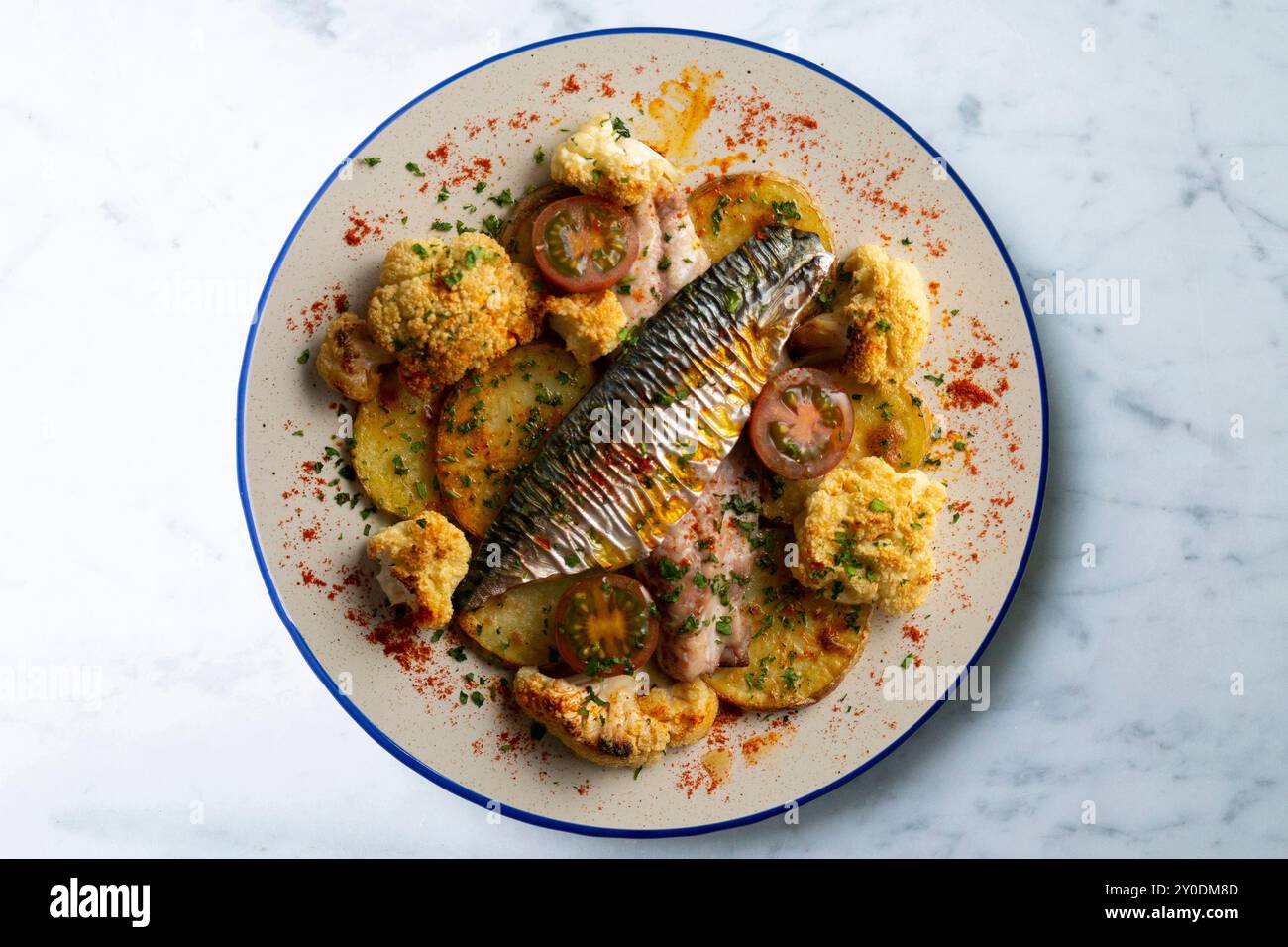 Gebackene Makrele mit geschmortem Blumenkohl und Kirschtomaten. Tabelle mit Draufsicht. Stockfoto