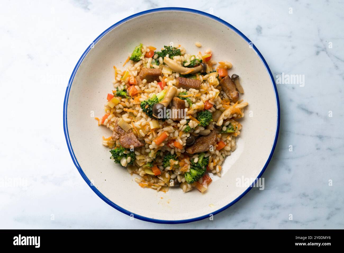 Reispaella mit Schweinelende, Pilzen und Brokkoli. Tisch mit Panoramablick und weihnachtsdekoration. Stockfoto