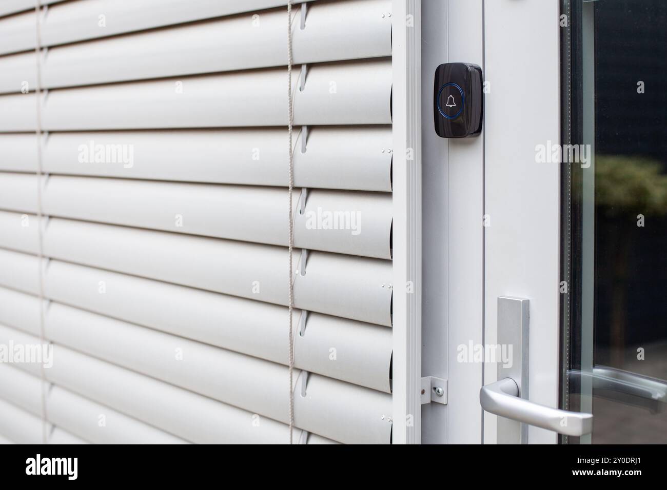 Geschlossene Fensterläden mit Türklingel an einer modernen Tür Stockfoto