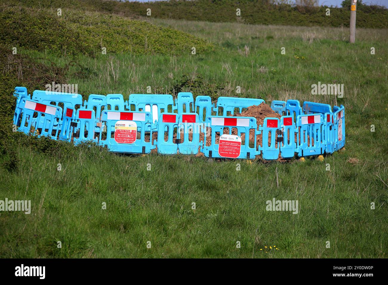 Eine Reparatur der Notwasserversorgungsleitung in den frühen Geschäftszeiten führte dazu, dass diese Arbeitsstätte und ein Loch in einem nahegelegenen Bauernfeld auftauchen. Stockfoto