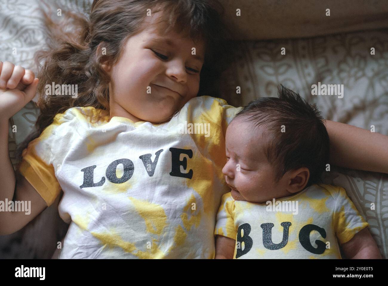 Geschwister in passenden „Love Bug“-Outfits teilen einen süßen Moment Stockfoto