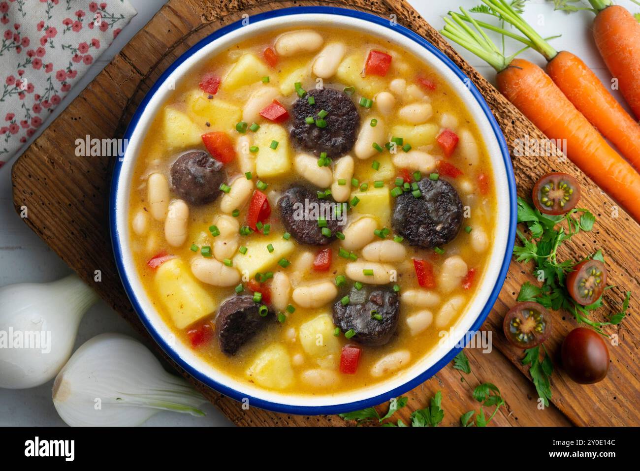 Bohneneintopf mit Schwarzpudding, Paprika und Kartoffeln. Tisch mit Draufsicht und Dekoration. Stockfoto