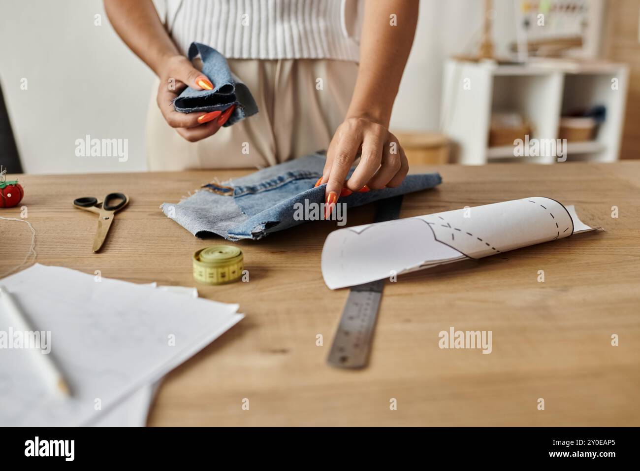 Eine Frau verwandelt Kleidungsstücke auf kreative Weise in einzigartige Modestücke. Stockfoto