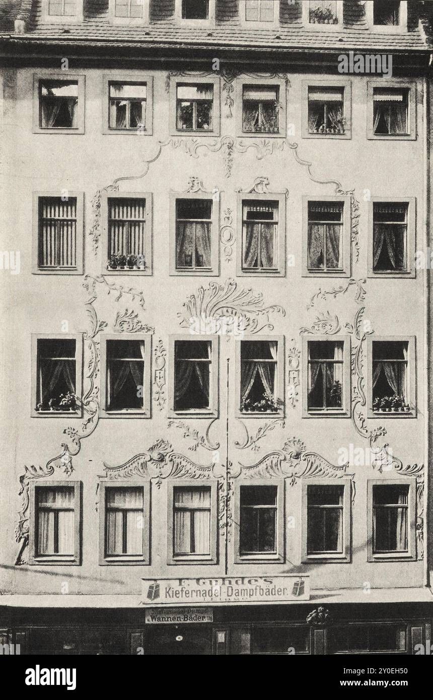 Vintage-Foto von Dresden. Altes Haus an der Moritzstraße Nr. 6. Deutschland. 1903 die fünfgeschossige, sechsfächerbreite Fassade zeigt eine schlichte Anordnung über dem komplett umgestalteten Erdgeschoss: Die Fenster umgeben unprofilierte Sandsteinwände. Die verputzten Flächen sind mit Rokoko-Ornamenten in appliziertem Stuck so verziert, dass durch die allgemeinen Pilaststreifen eine pyramidale Struktur erreicht wurde. Das Gebäude muss kurz nach der Belagerung von 1760 errichtet worden sein. Eine große Kanonenkugel ist in den Innenhof eingemauert. Stockfoto