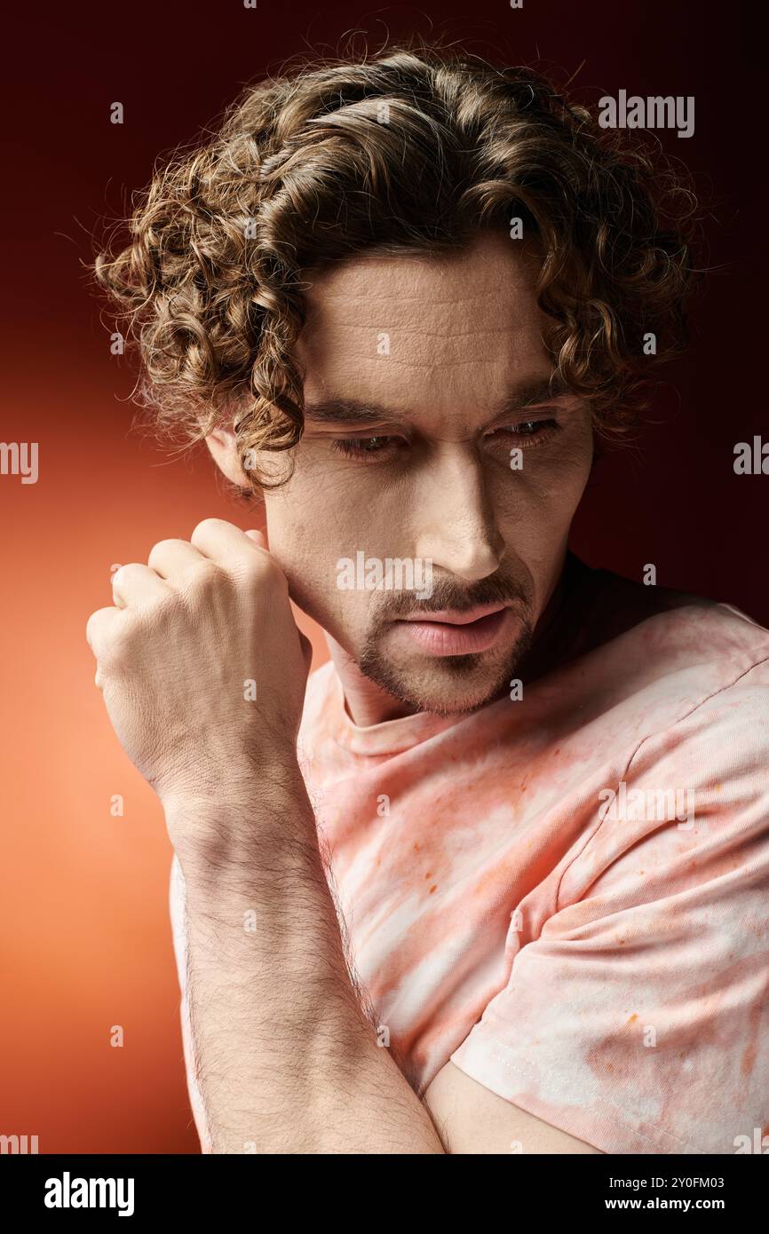 Ein gutaussehender Mann vermittelt tiefe Emotionen vor einem auffälligen Hintergrund. Stockfoto