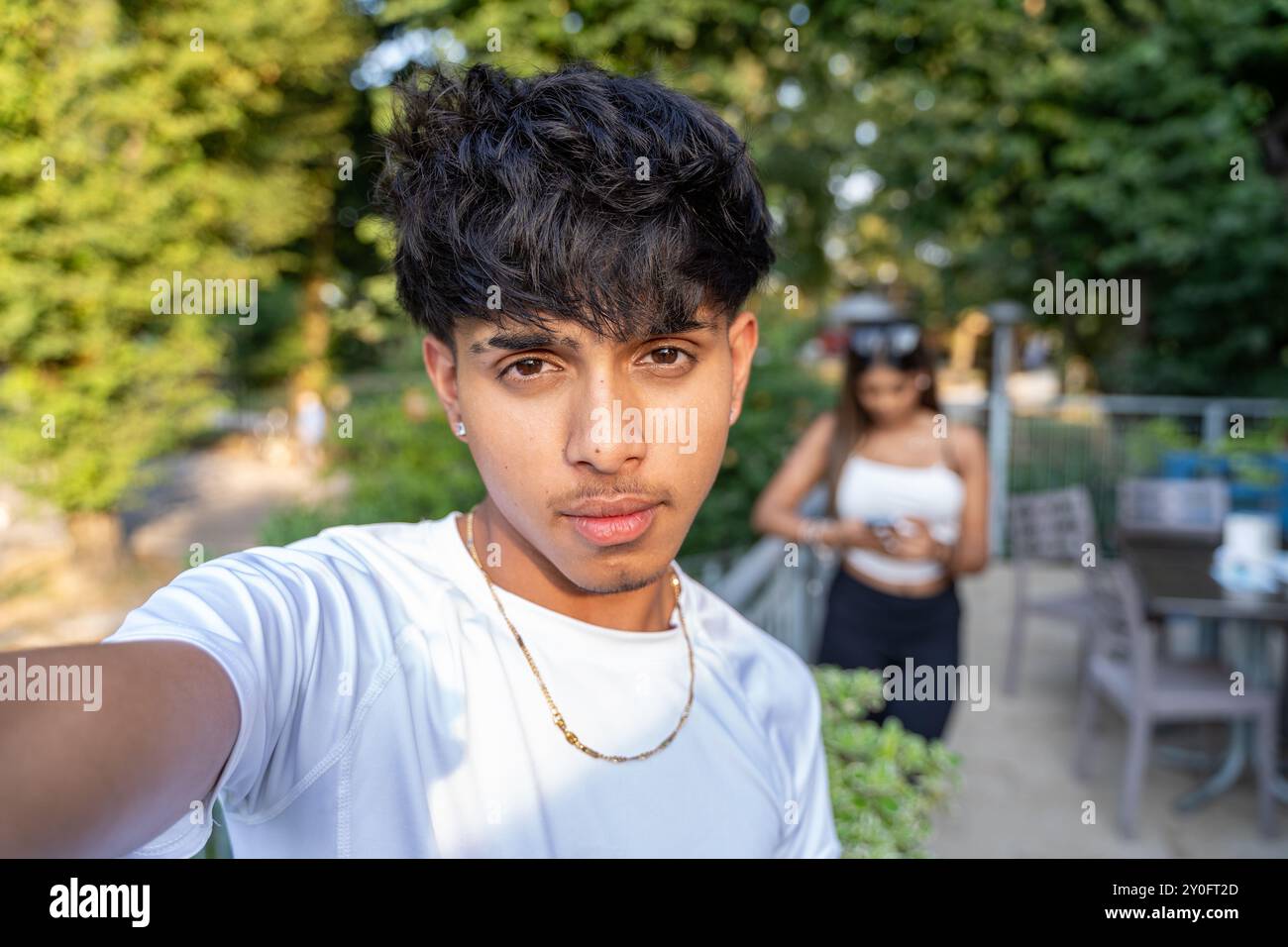 Junger, freundlich lächelnder Teenager, der ein Selfie auf der Terrasse eines Restaurants im Freien macht Stockfoto