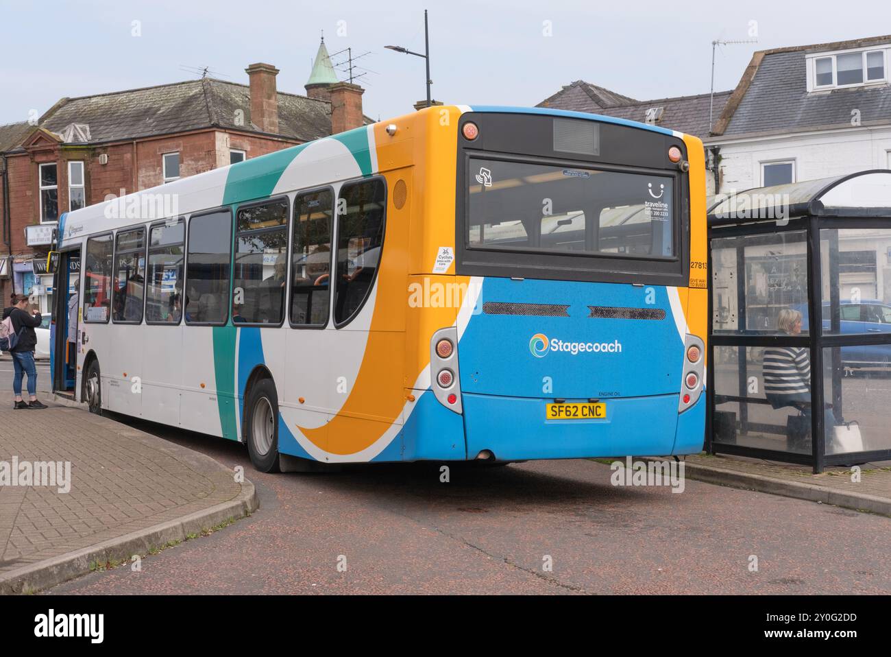Die Leute stehen an, um in einen einstöckigen Stagecoach-Bus im Whitesands, Dumfries Stadtzentrum, Schottland, zu steigen. Eine Bushaltestelle in der Nähe zeigt den engen Raum. Stockfoto