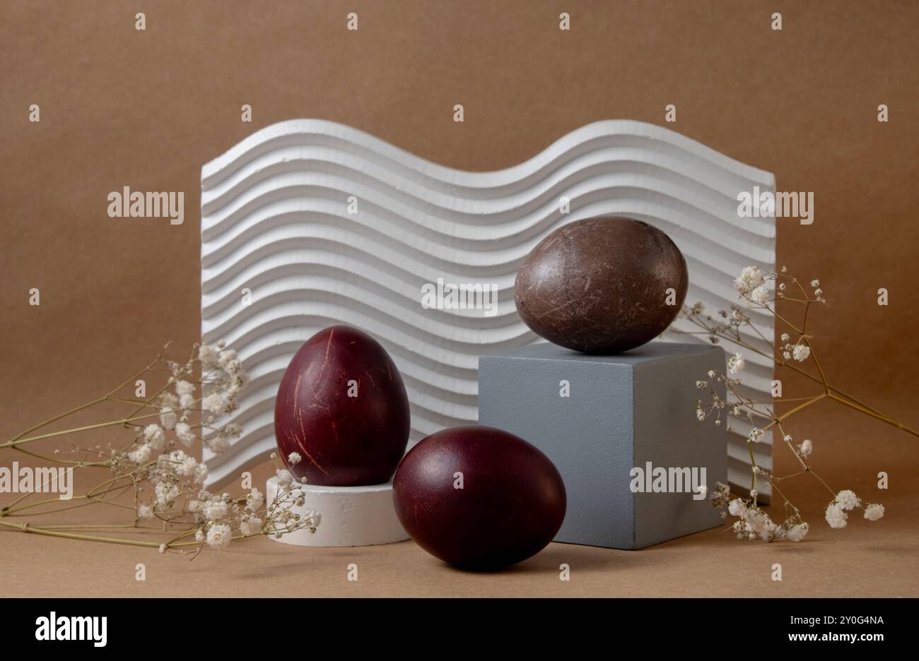 Ein kreatives Arrangement brauner ostereier in Braun und Kastanienbraun, auf geometrischen Formen mit weißem welligen Hintergrund. Komposition hebt Kontrast A hervor Stockfoto