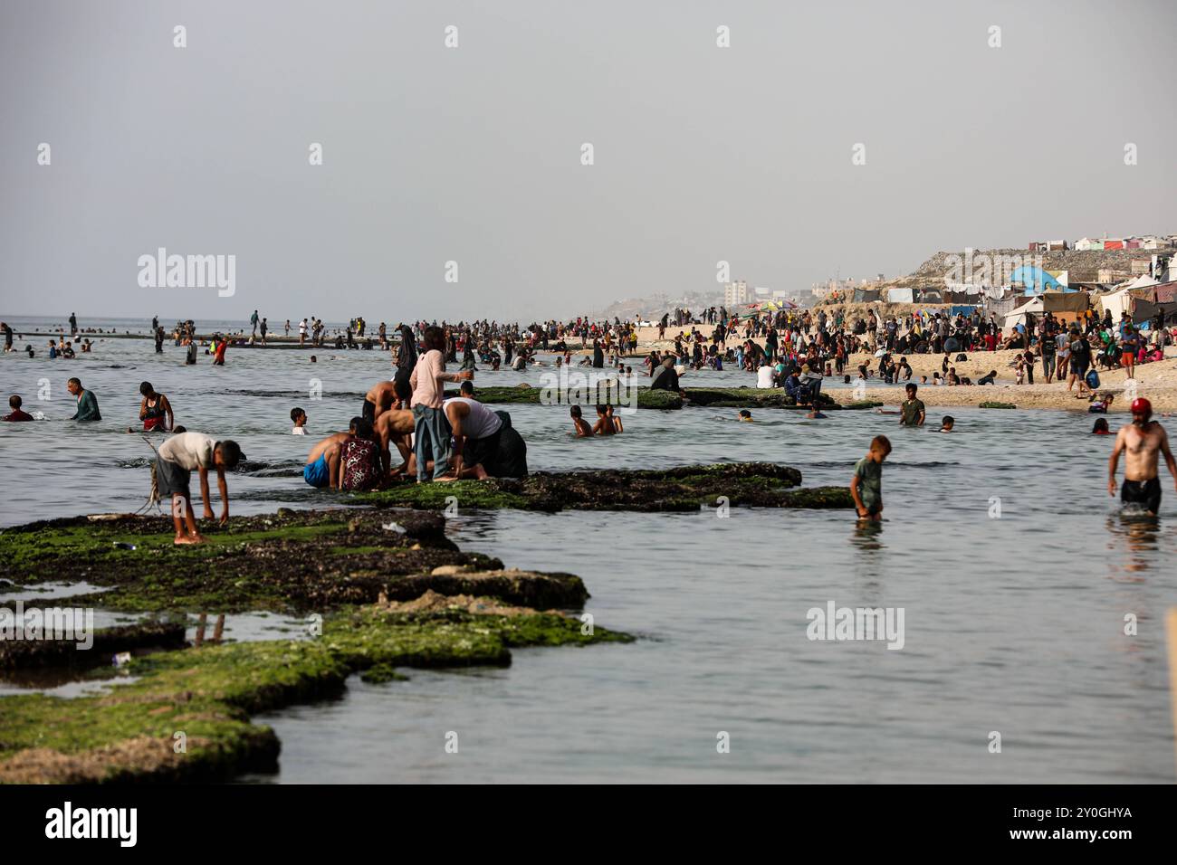 Deir al-Balah, Gazastreifen, Palästina. 20. Mai 2024. Palästinenser baden im Meer nahe Deir al Balah, im Zentrum des umkämpften Gazastreifens. Trotz mehr als sieben Monate heftiger israelischer Bombardements und ohne sicheren Ort in der palästinensischen Enklave besuchen die Bewohner des Gazastreifens die Küste, um sich kurz vom Krieg und der intensiven Hitze ihrer nahegelegenen Umzugszelte zu erholen Stockfoto