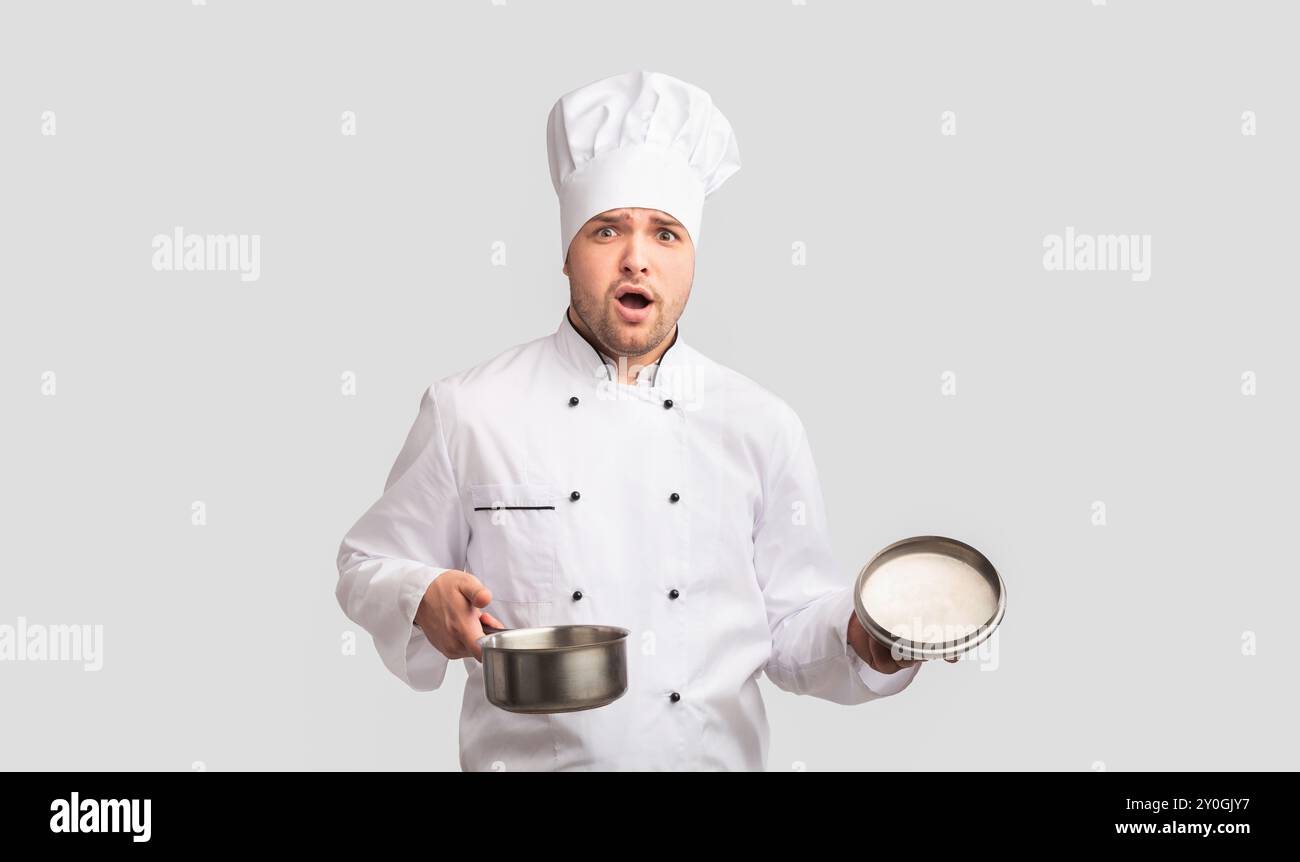 Verwirrt Cook Mann Öffnung Topf stehen auf weißen Studio Hintergrund Stockfoto