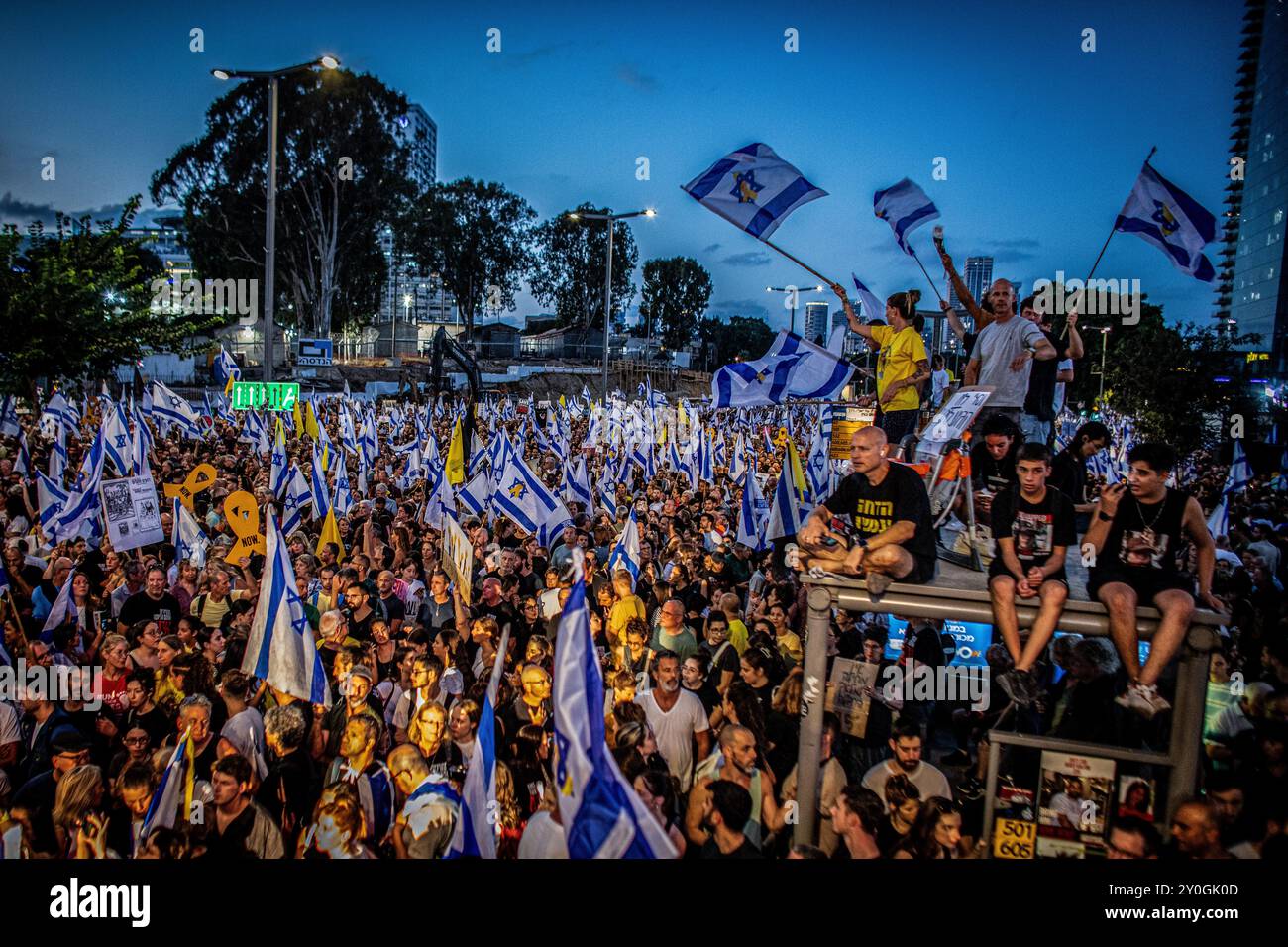 Tel Aviv, Israel. September 2024. Die Demonstranten schleuderten Flaggen während der Demonstration. Die Organisatoren behaupten, dass sonntagabends über 700.000 Israelis in Städten im ganzen Land auf die Straßen gedrungen sind, nachdem die Leichen von Karmel Gat, Eden Yerushalmi, Hersh Goldberg-Polin, Alexander Lobanov, Almog Sarusi und Meister Sgt Ori Danino aus Gaza gerettet wurden. Demonstranten forderten, dass Premierminister Benjamin Netanjahu einen Waffenstillstand mit der Hamas eingeht, um die verbliebenen Gefangenen nach Hause zu bringen. Quelle: SOPA Images Limited/Alamy Live News Stockfoto