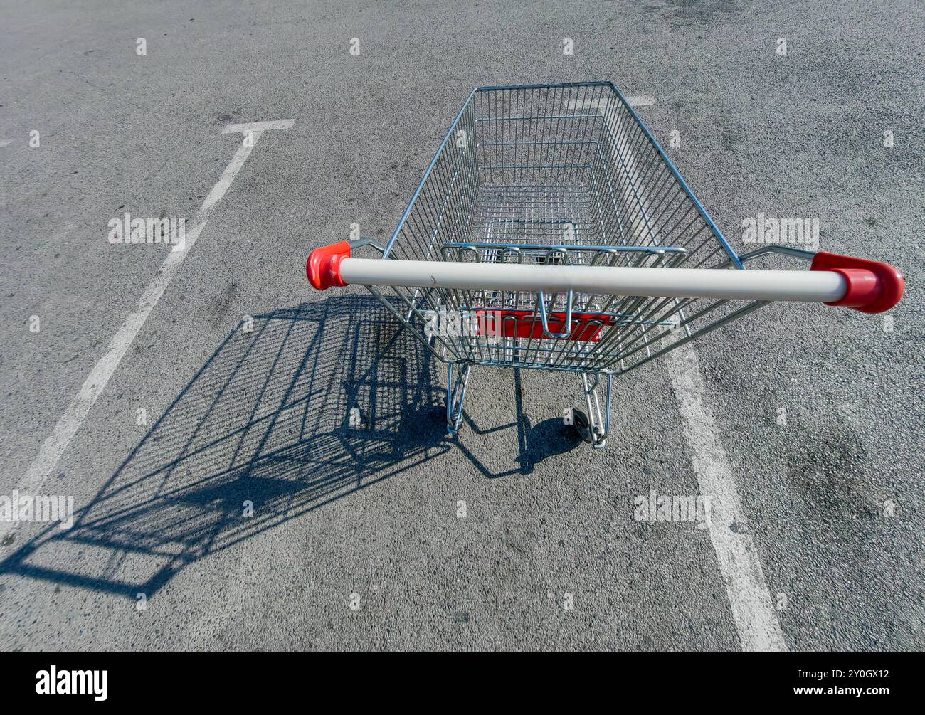 Leerer Einkaufswagen auf dem Parkplatz: Ein Symbol für wirtschaftliche Kämpfe und harte Zeiten. Stockfoto