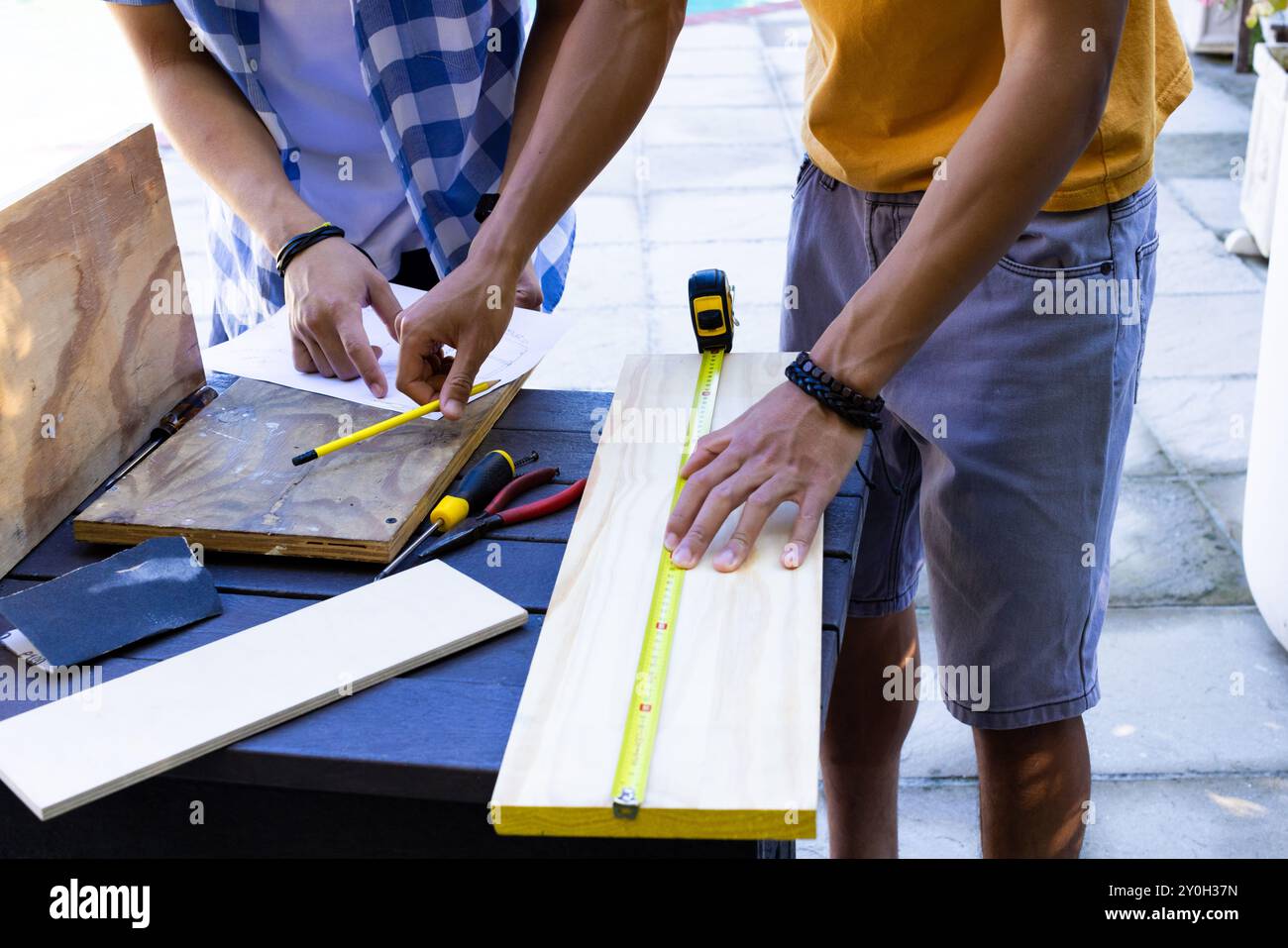 Holz vermessen und markieren, asiatischer Vater und Teenager-Sohn arbeiten an einem Schreinerprojekt im Freien Stockfoto