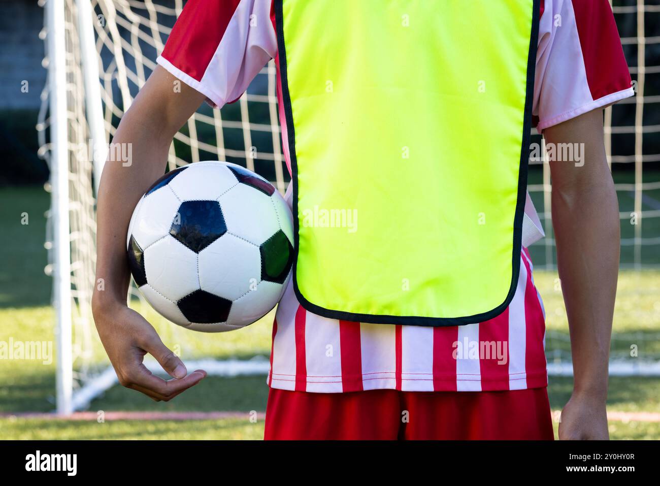 Fußball halten, Spieler in gelber Weste in der Nähe des Tornetzes stehen, Kopierraum Stockfoto
