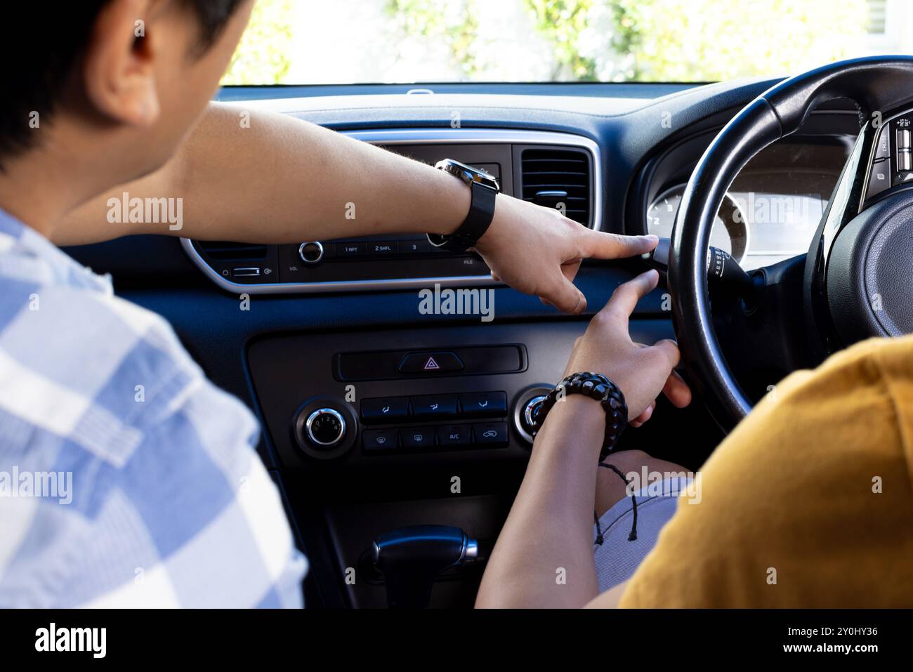 Er zeigt auf das Armaturenbrett des Autos, ein asiatischer Mann, der einem anderen asiatischen Mann seine Fahrkünste beibringt Stockfoto