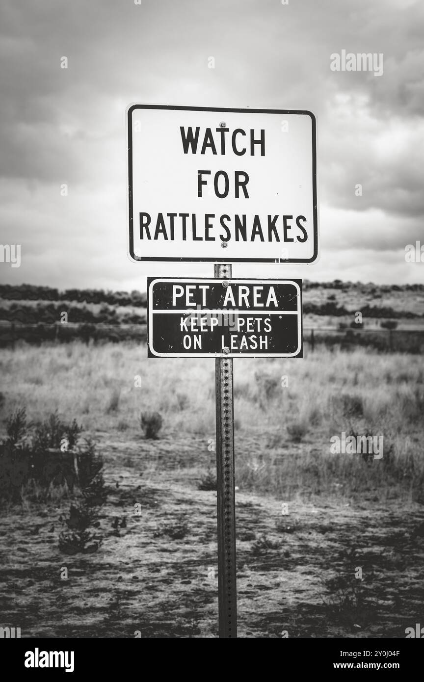 Ein Schild für Klapperschlangen in der Nähe einer Haltestelle des Washington State Highway. Schwarzweißbild. Stockfoto