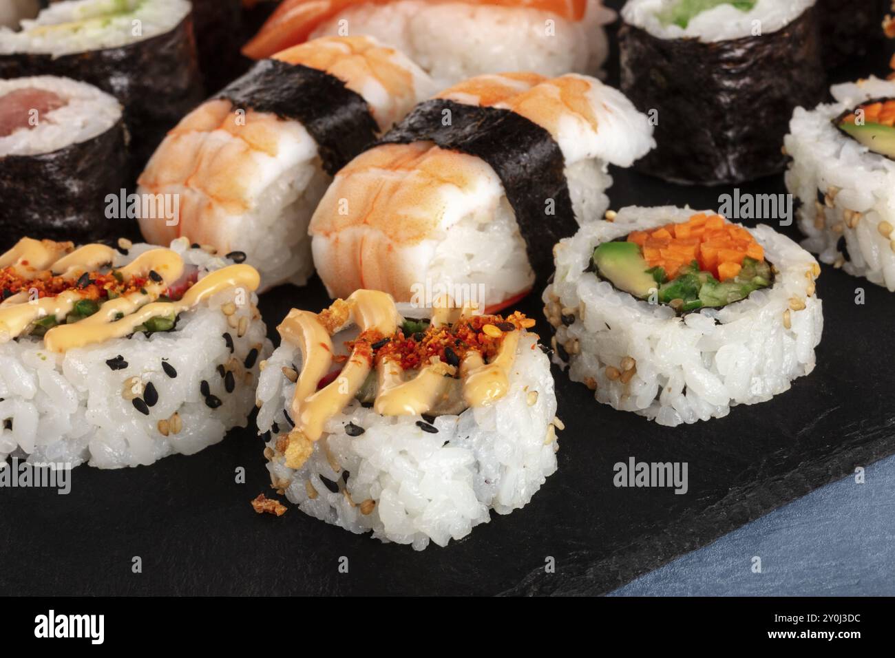 Großes Sushi im Nahaufnahme. Maki, Nigiri und rollt auf einem schwarzen Schiefer Stockfoto