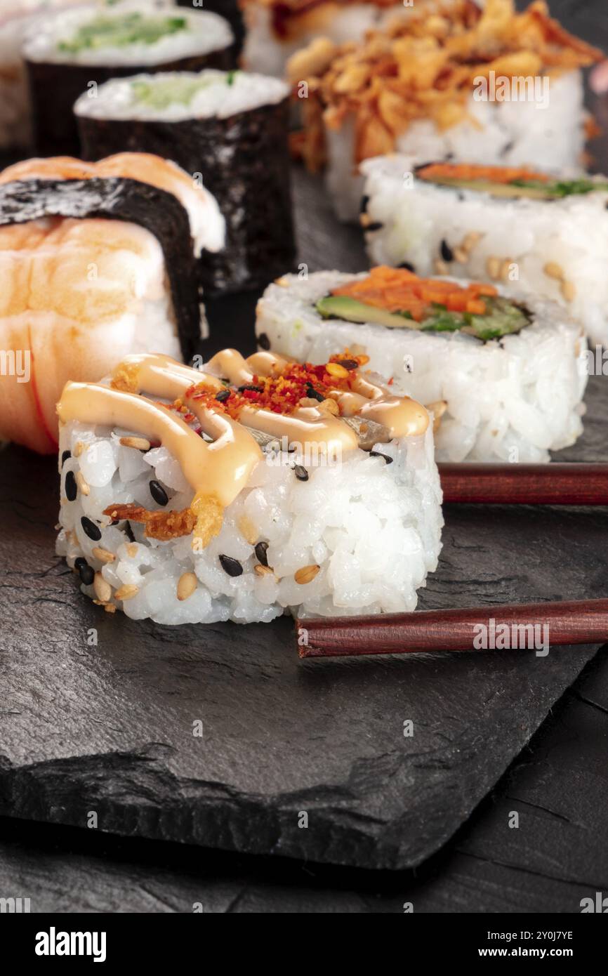 Sushi Nahaufnahme mit Essstäbchen auf schwarzem Hintergrund Stockfoto