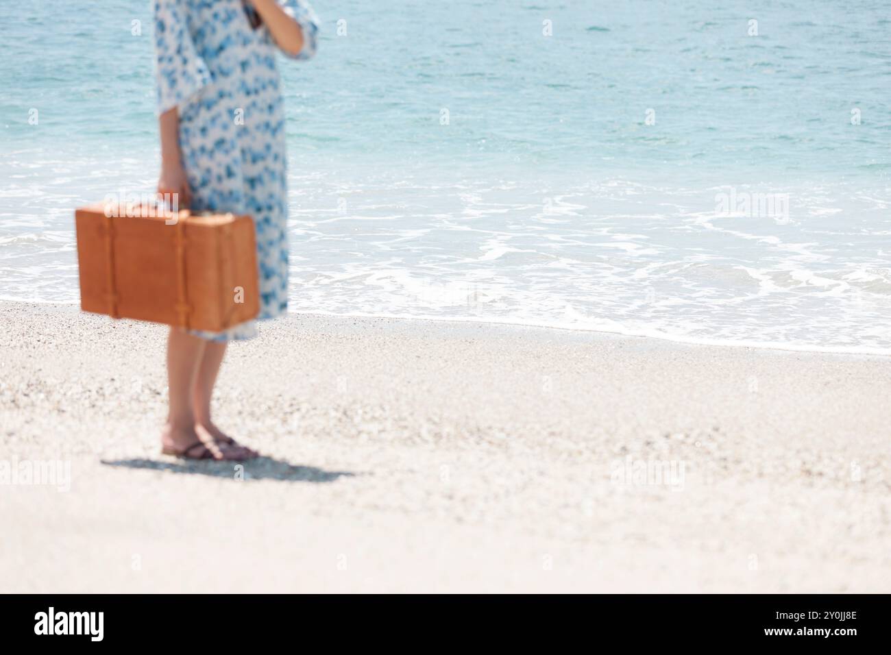 Frau, die mit einer Reisetasche am Strand läuft Stockfoto