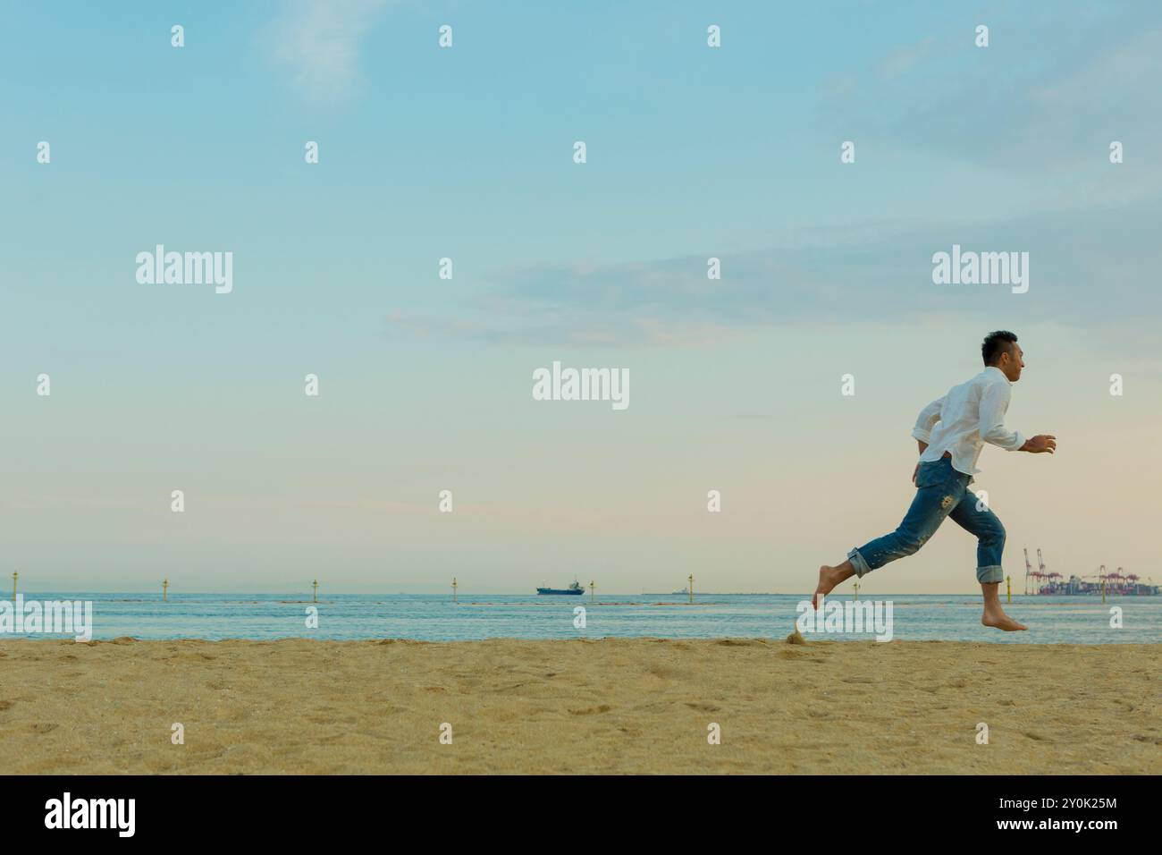 Ein japanischer Mann, der am Strand läuft Stockfoto
