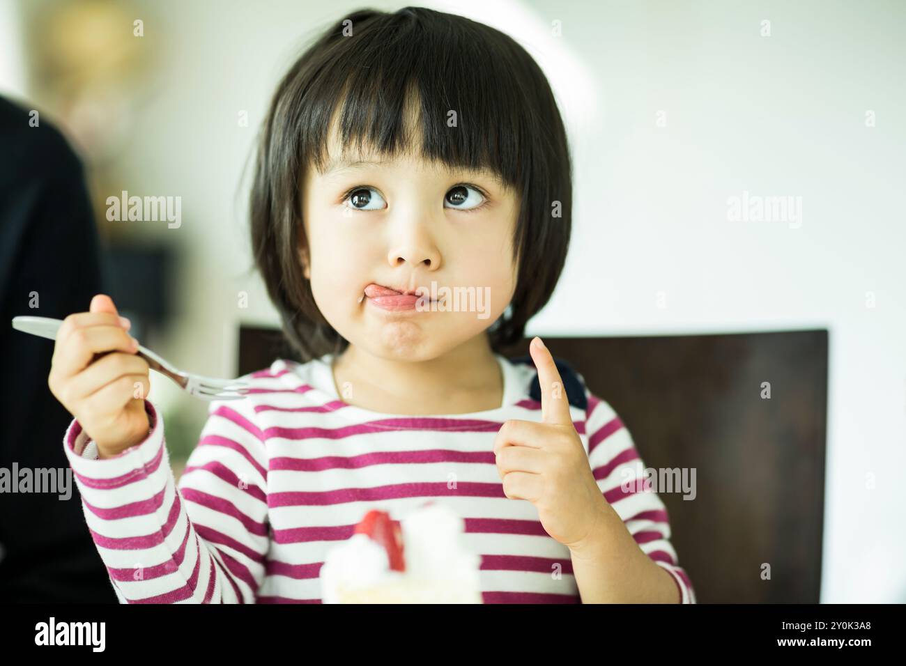 Mädchen leckt Creme, die an ihrer Wange klebte Stockfoto