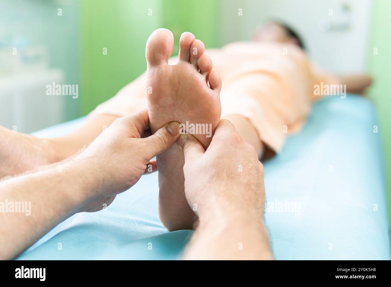 Frau erhält eine Fußmassage im Wellnesscenter. Konzept der Massage-Spa-Behandlungen. Ein professioneller männlicher Masseur kniet einer jungen Frau den Fuß. Stockfoto