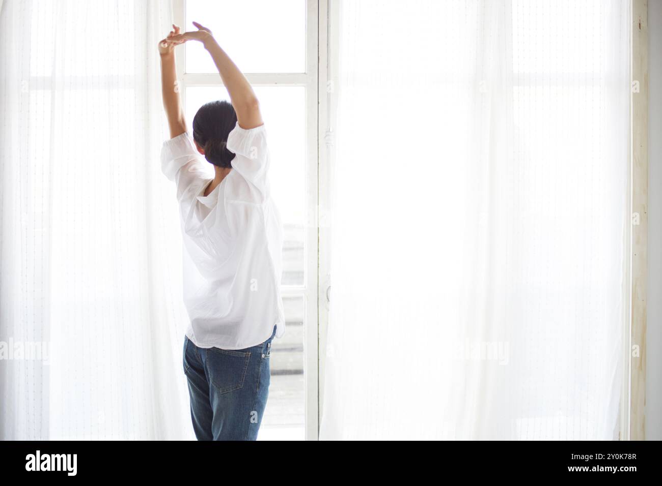 Frau, die sich am Fenster ausdehnt Stockfoto