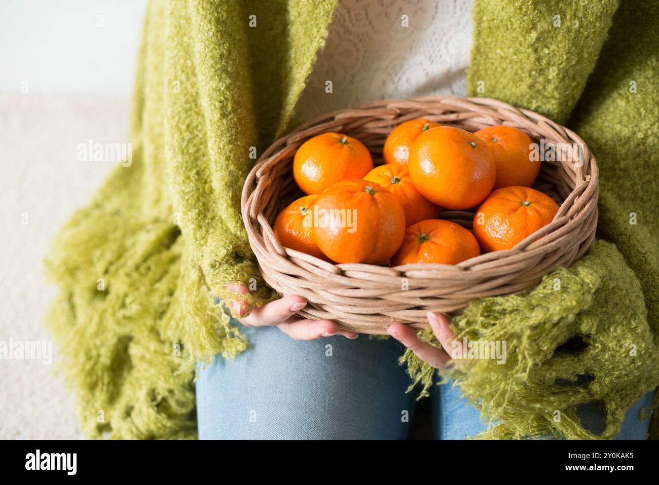 Hand einer Frau, die eine Mandarine in einem Korb hält Stockfoto