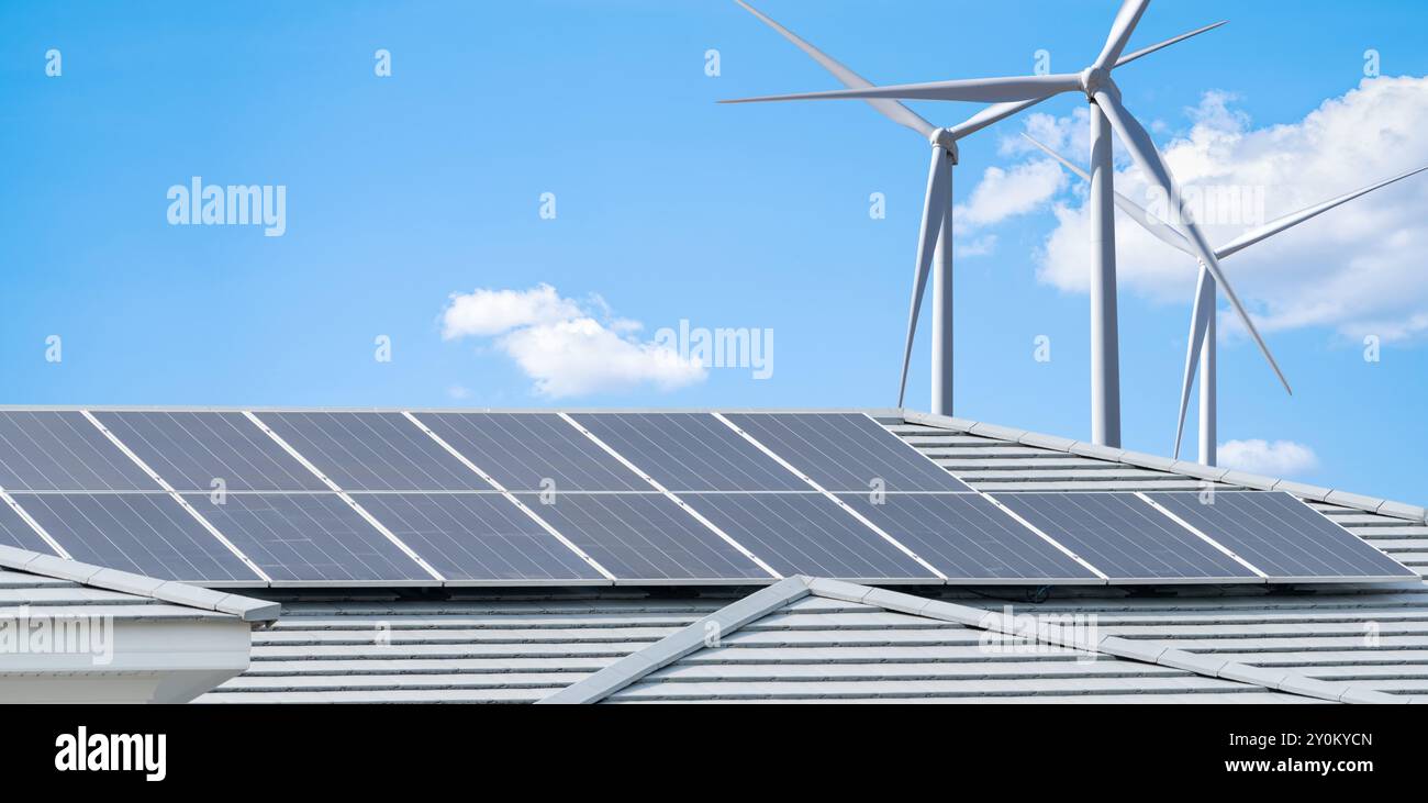 Solarpaneele auf dem Dach von Wohngebäuden und Windkraftanlagen erzeugen sauberen Strom für städtische Wohnhäuser. Nachhaltiger Strom für umweltfreundliche Stadtteile Stockfoto
