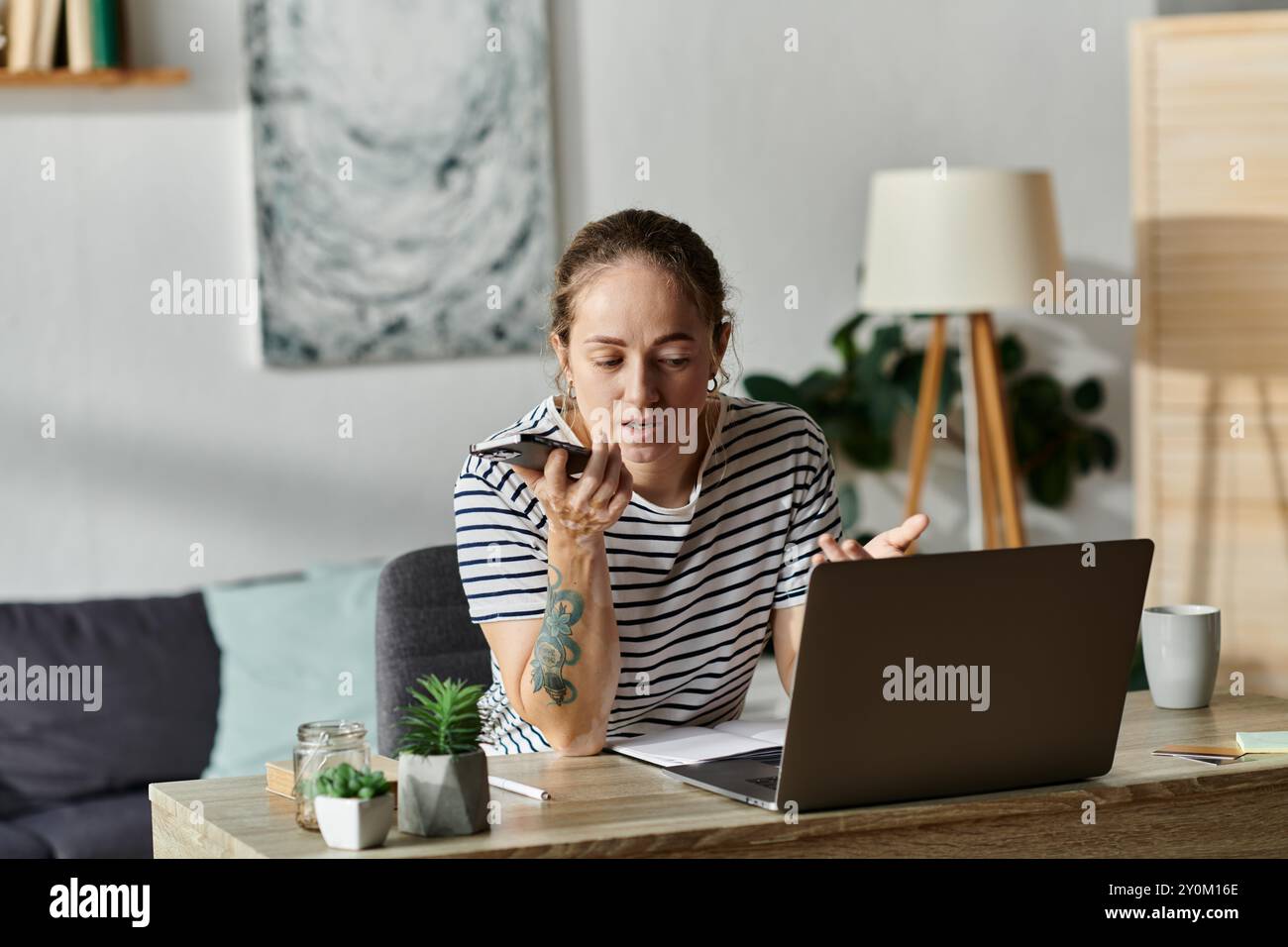 Junge Frau mit Vitiligo spricht aktiv am Smartphone in gemütlichem Arbeitsbereich. Stockfoto