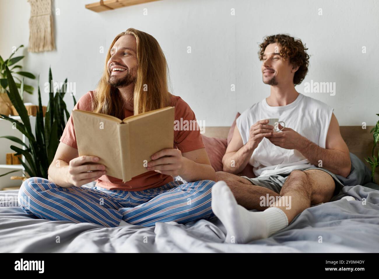 Zwei Partner genießen gemütliche Momente zusammen, lesen und trinken Kaffee. Stockfoto