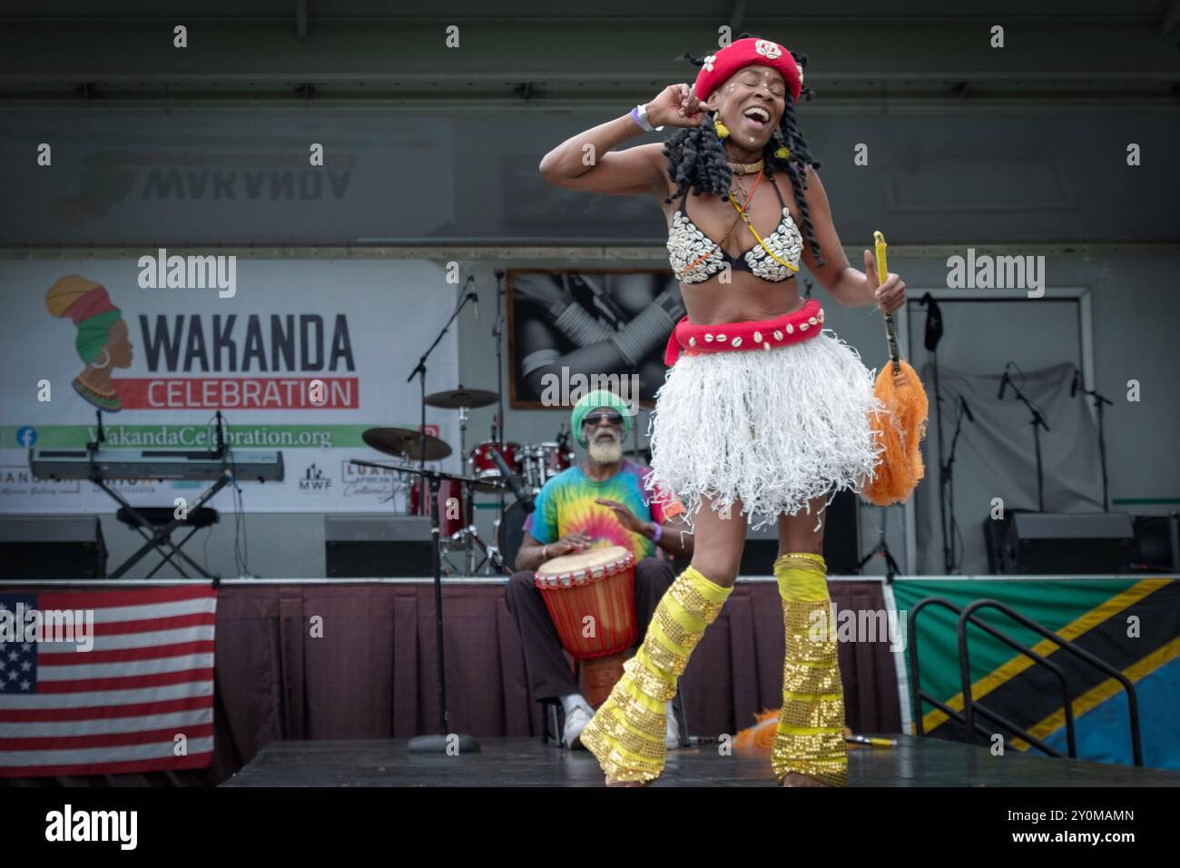 Begleitet von einem einzigen Schlagzeuger tritt eine attraktive Tänzerin in kongolesischer Kleidung auf. Auf der Wakanda 2024 in Mount Vernon, New York. Stockfoto