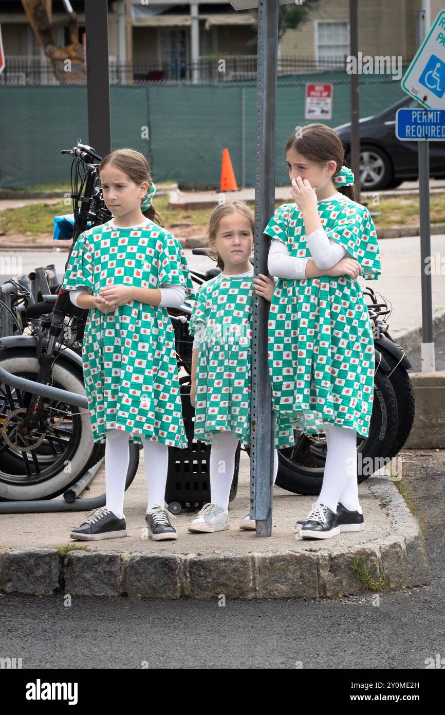 3 bescheiden gekleidete orthodoxe jüdische Schwestern warten auf eine Fahrt auf einem Parkplatz in Monsey, Rockand County, New York. Stockfoto