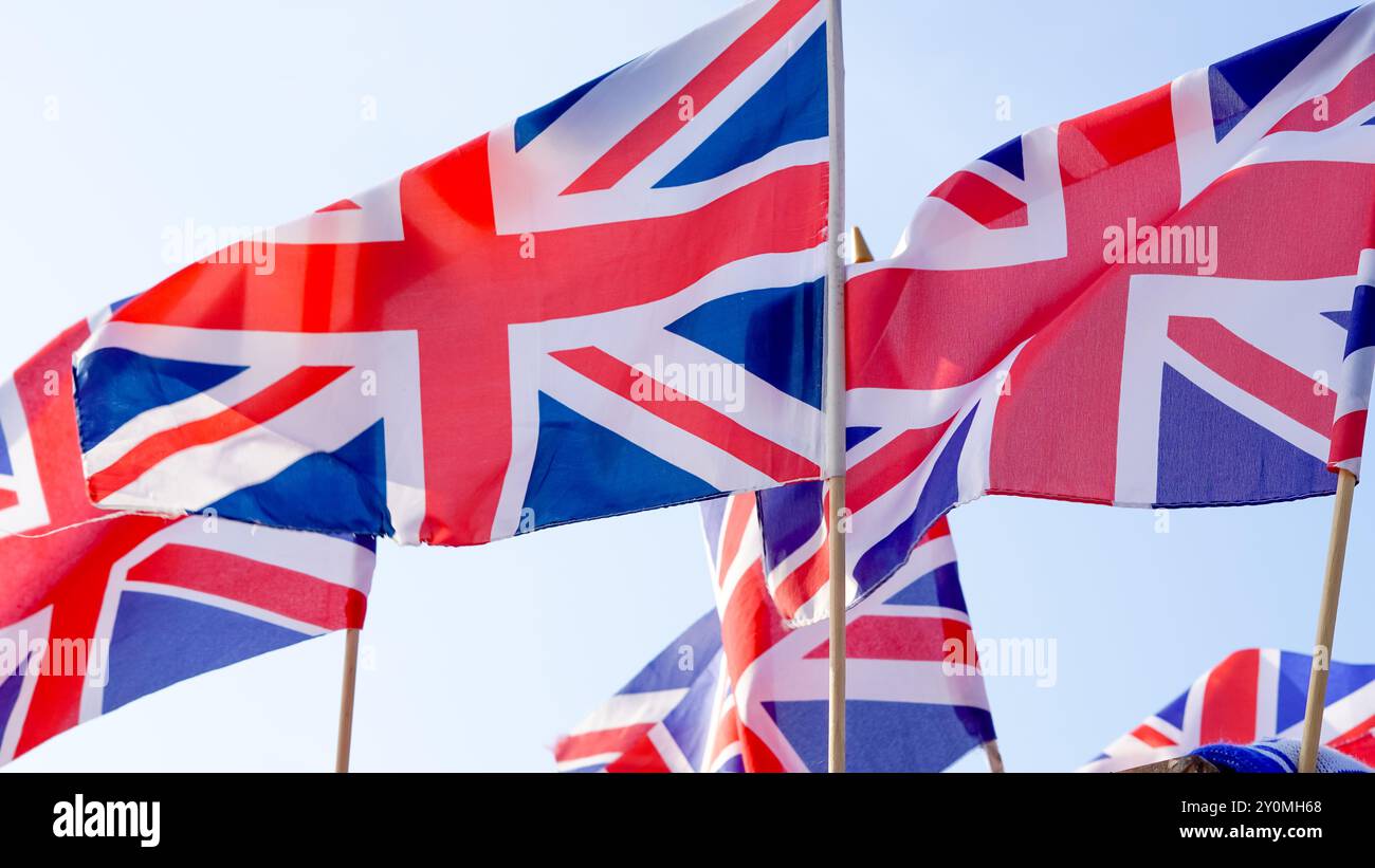 Britische Flaggen winken vor einem klaren blauen Himmel und symbolisieren nationalen Stolz und Identität. Stockfoto