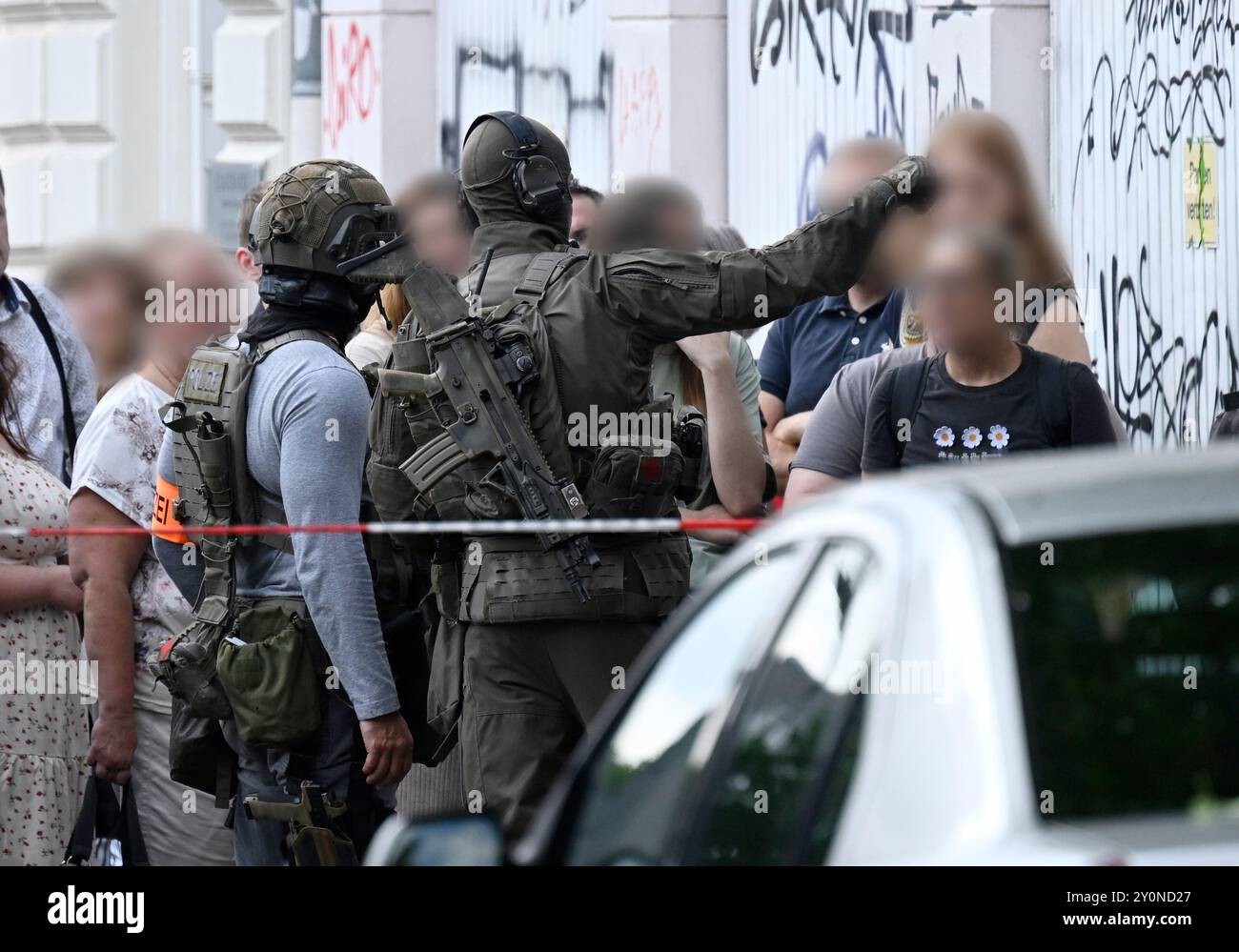 Wuppertal, Deutschland. September 2024. Polizeibeamte mit Spezialausrüstung sichern den Bereich um die Arbeitsagentur und sprechen mit Mitarbeitern der Arbeitsagentur, die das Gebäude verlassen haben. In Wuppertal ist ein großer Polizeieinsatz rund um die Arbeitsagentur im Gange. Ein Polizeisprecher sagte, dass mehr Truppen und mindestens ein Helikopter eingesetzt werden. Hinweis: Roberto Pfeil/dpa - ACHTUNG: Person(en) wurde/wurden aus Datenschutzgründen pixeliert./dpa/Alamy Live News Stockfoto