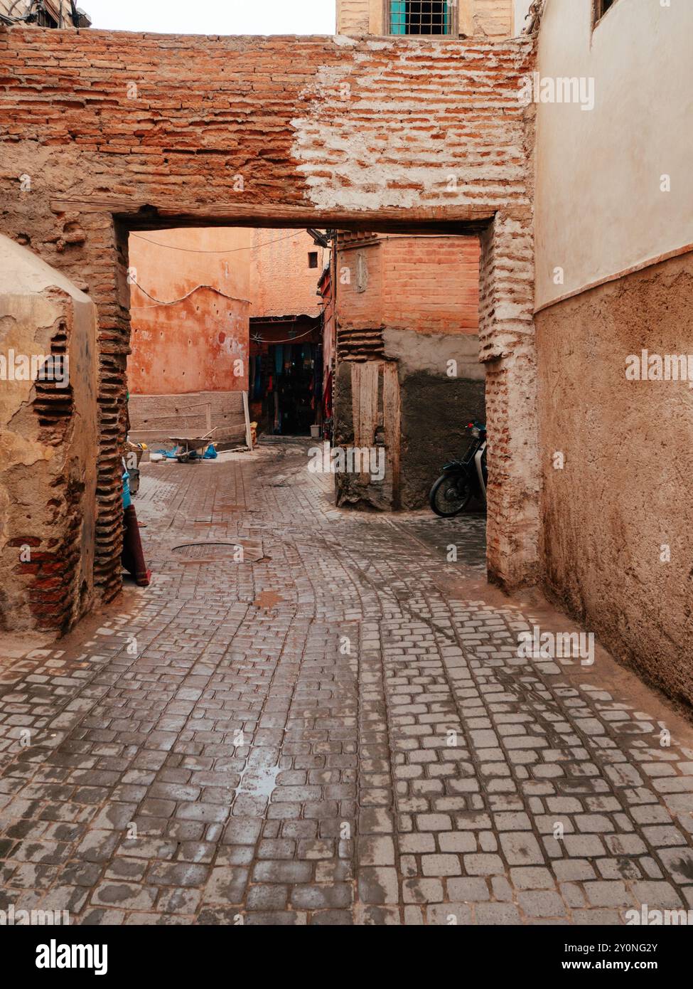 Eine enge Gasse in einer marokkanischen Medina bietet Kopfsteinpflasterpflasterpfade, die von strukturierten Wänden flankiert werden, mit einer einladenden Atmosphäre, während der späte Nachmittag aufleuchtet Stockfoto