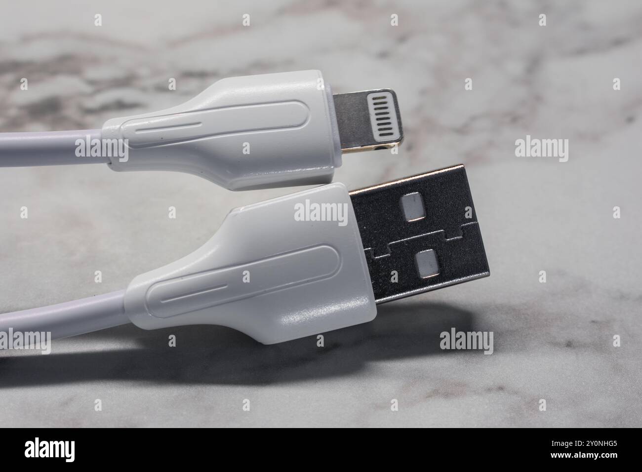 Weißes Lightning-Kabel zum Aufladen und Synchronisieren vor hellem Hintergrund, das sein schlankes und funktionales Design unterstreicht. Stockfoto