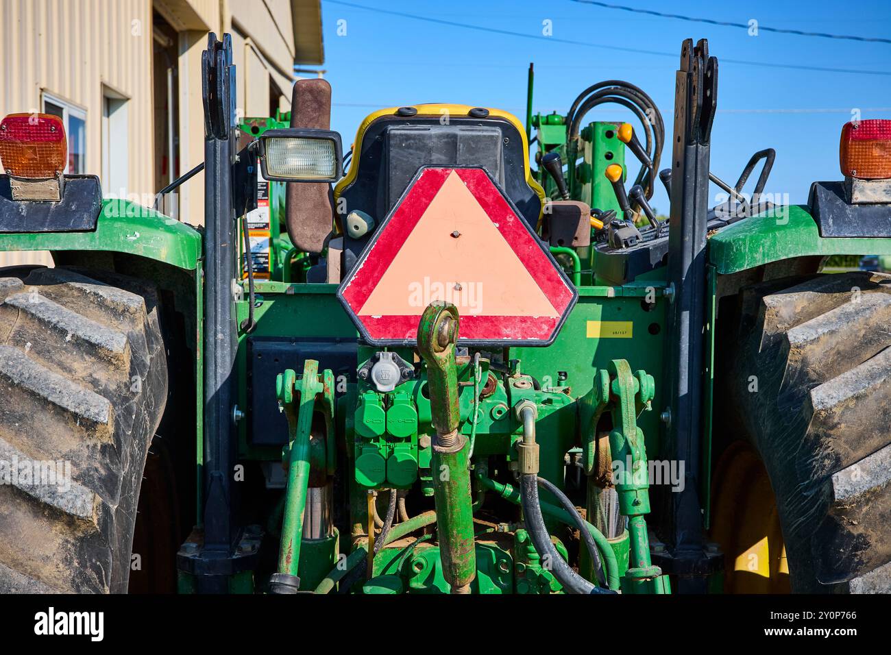 Rückansicht des grünen Traktors mit SMV-Emblem und robusten Reifen in Augenhöhe Stockfoto